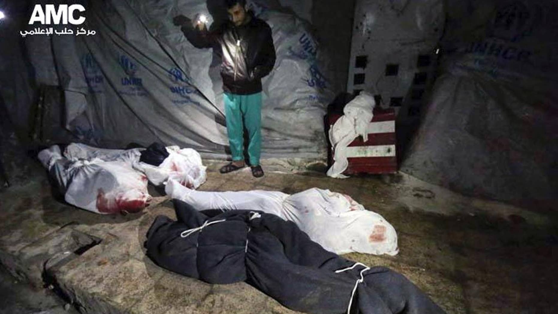 Feb. 5, 2015 - Syrian man stands next to bodies that were, according to activists, killed from an airstrike by the Syrian government forces in Aleppo, Syria. Syrian army helicopters dropped 2 barrel bombs on a crowded square in the northern city of Aleppo, killing tens of civilians as they sat on a bus and collected water, activists said Friday.