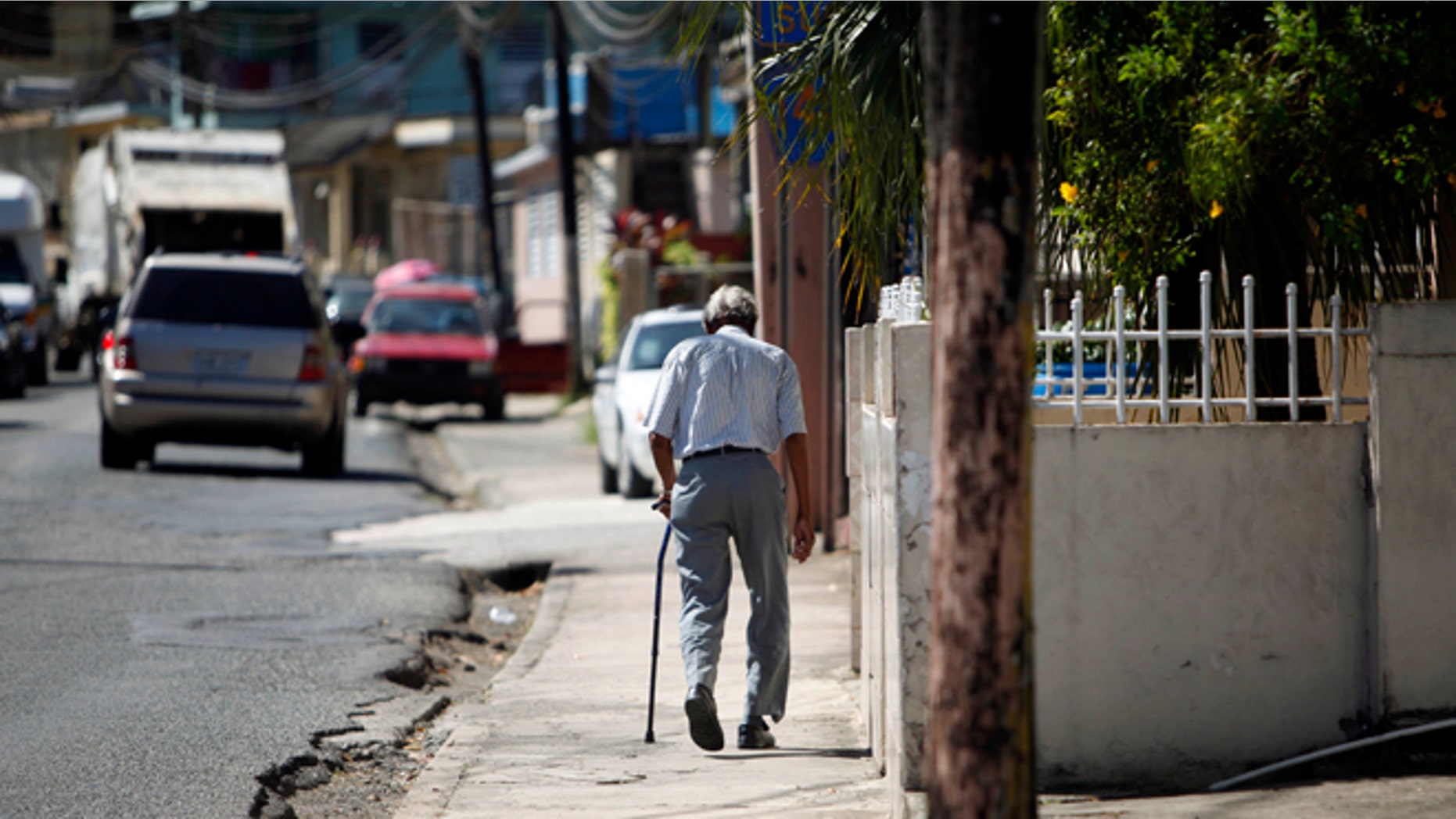In this Nov. 14, 2013 photo, Mariano Perez Morales, 75, walks a sidewalk in Barceloneta, Puerto Rico.