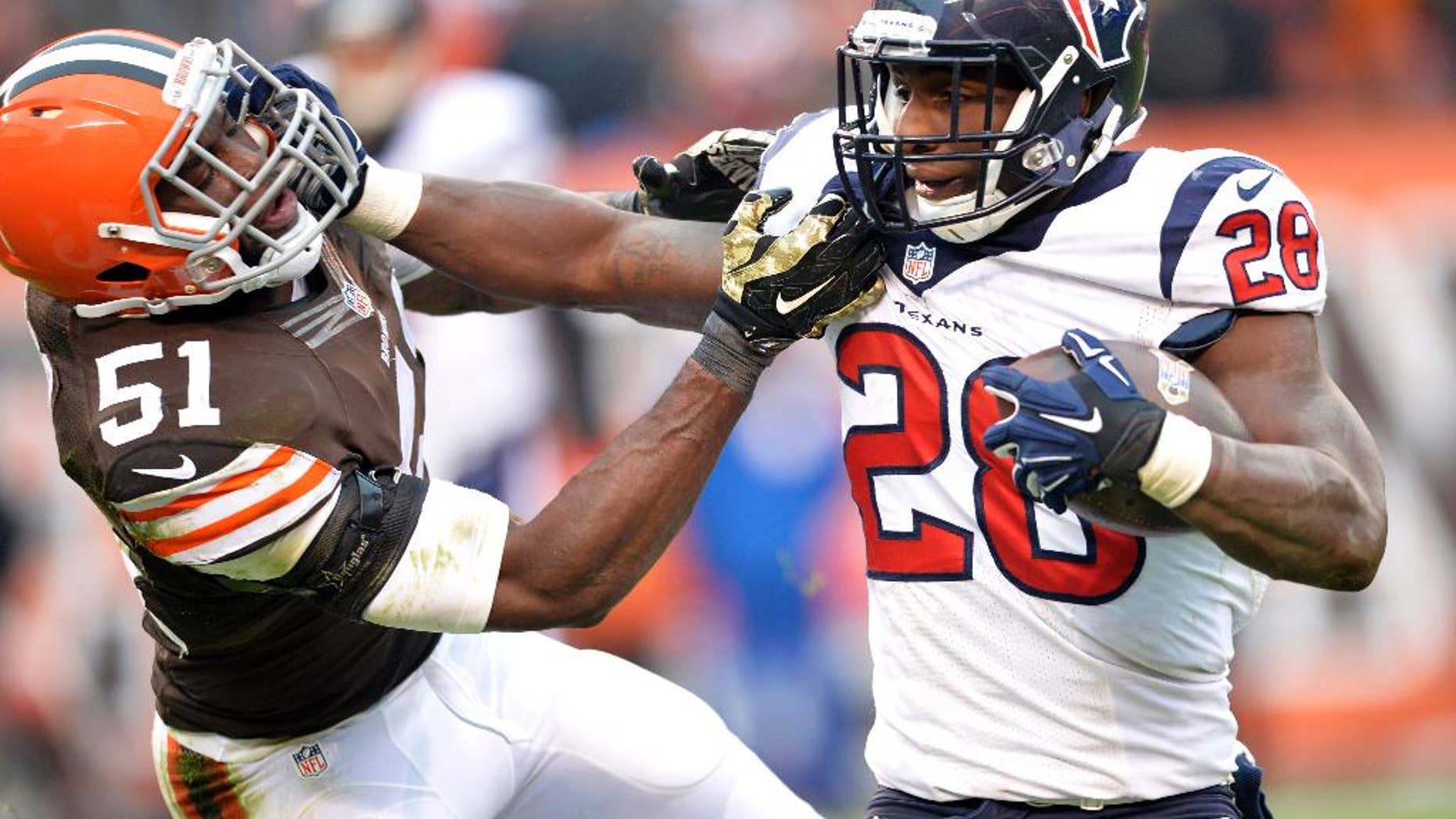 Houston Texans running back Alfred Blue (28) fights for yardage against Cleveland Browns outside linebacker Barkevious Mingo (51) in the fourth quarter of an NFL football game Sunday, Nov. 16, 2014, in Cleveland. (AP Photo/David Richard)