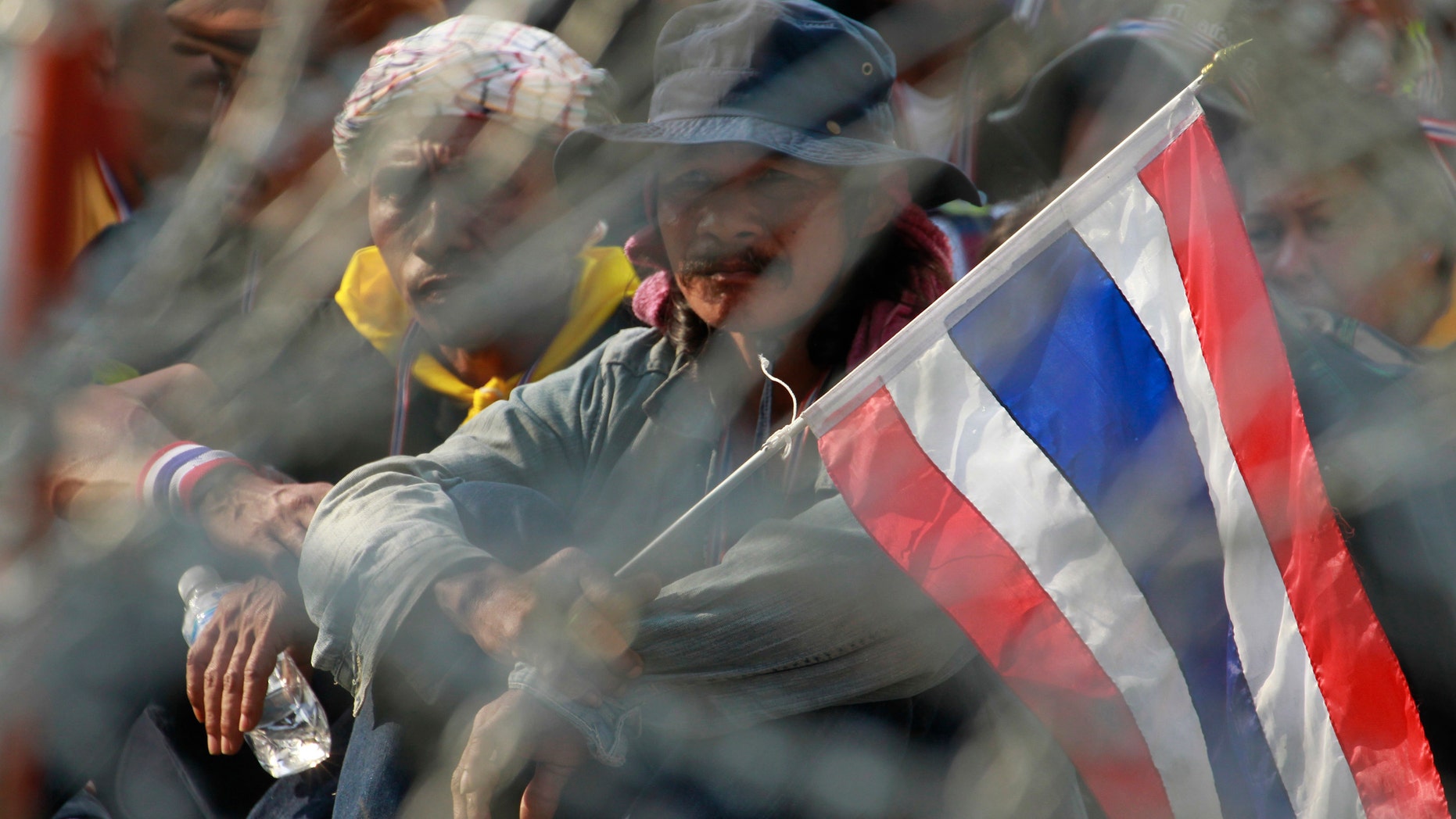 Anti-government protesters take their positions behind barbed wire during a rally outside the office of the permanent secretary for defense where Prime Minister Yingluck Shinawatra was reportedly working inside Monday, Feb. 3, 2014 in Bangkok, Thailand. Thai protesters vowed Monday to stage larger rallies in central Bangkok and push ahead their efforts to nullify the results of elections that were expected to prolong a national political crisis. (AP Photo/Wason Wanichakorn)