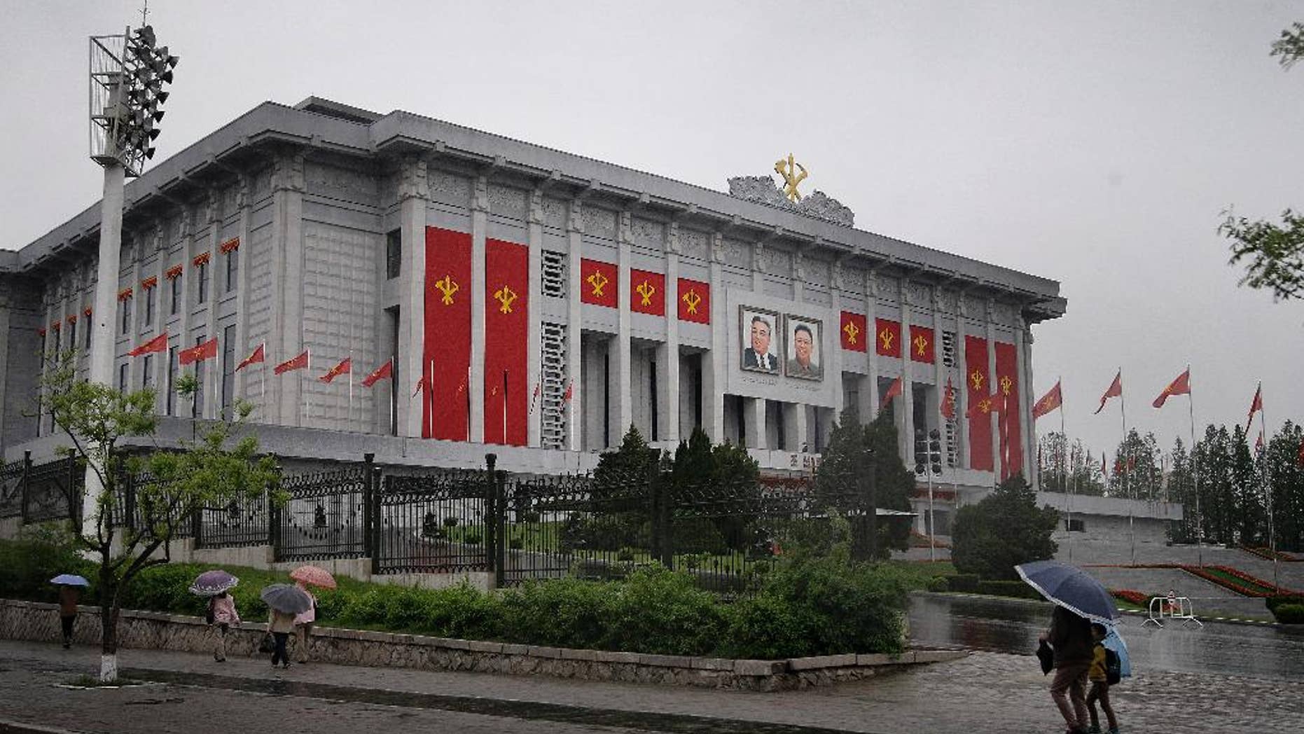 In this Thursday, May 5, 2016, photo, North Koreans walk past the April 25 House of Culture decorated in the colors and flags of their ruling party, Workers' Party, in Pyongyang, North Korea. North Korea’s elite are gathered in Pyongyang ahead of their biggest political conference in decades. Foreign experts say leader Kim Jong Un will likely use the meeting, which starts Friday, to push his expansion of a nuclear arsenal over the strong objections of the U.S., the U.N. and North Korea's neighbors, including ally China. (AP Photo/Wong Maye-E)