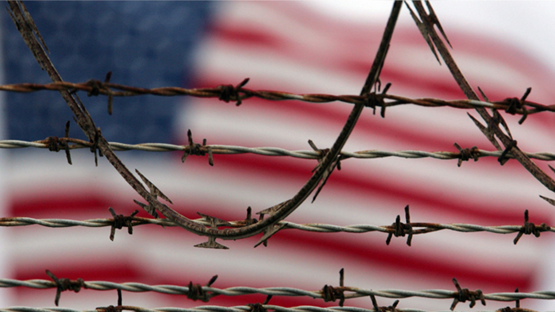 ** FILE ** In this Oct. 10, 2007 file photo, reviewed by the U.S. Military, an American flag flies behind the barbed and razor-wire at the Camp Delta detention facility, at Guantanamo Bay U.S. Naval Base, Cuba. The Pentagon said Saturday that four Afghans from the Guantanamo Bay detention center have been returned to their home country in what U.S. officials are citing as a sign of their confidence in new Afghan President Ashraf Ghani. (AP Photo/Brennan Linsley)