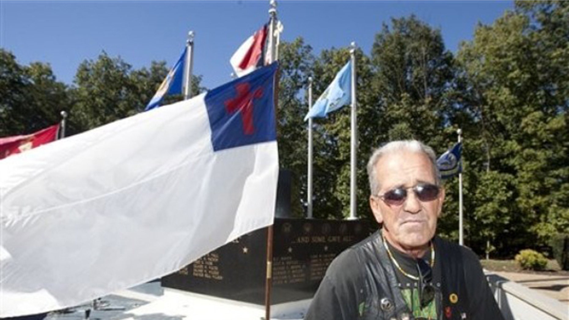 Oct. 16: Ray Martini, an Air Force Veteran, stands beside a Christian flag flying in front of the Veterans Memorial at Central Park in King, N.C. (AP).