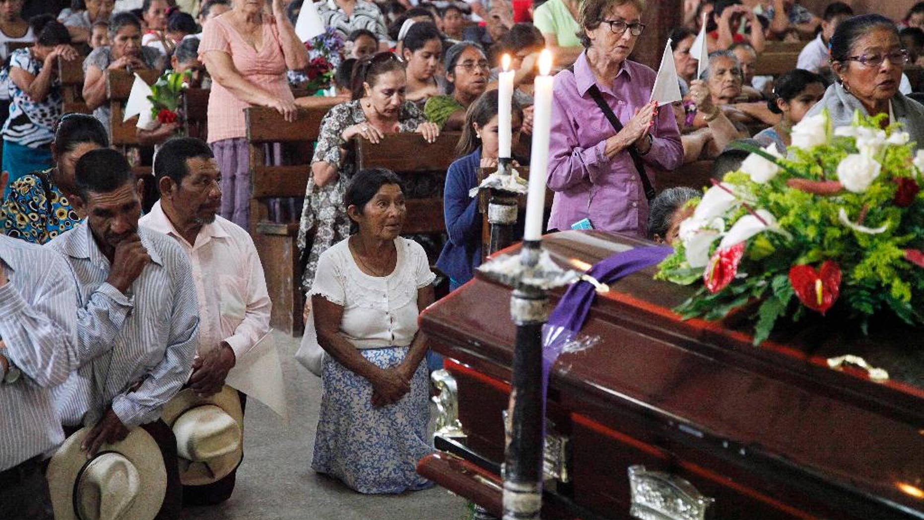 People pray by the coffin of slain Lesbia Janeth Urquia, an environmentalist and indigenous rights activist, during Mass in Marcala, Honduras, Friday, July 8, 2016. Authorities say Urquia's body was found Wednesday in a garbage dump in Marcala. Urquia's assassination comes four months after the murder of award-winning environmentalist Berta Caceres stirred international outrage. (AP Photo/Fernando Antonio)