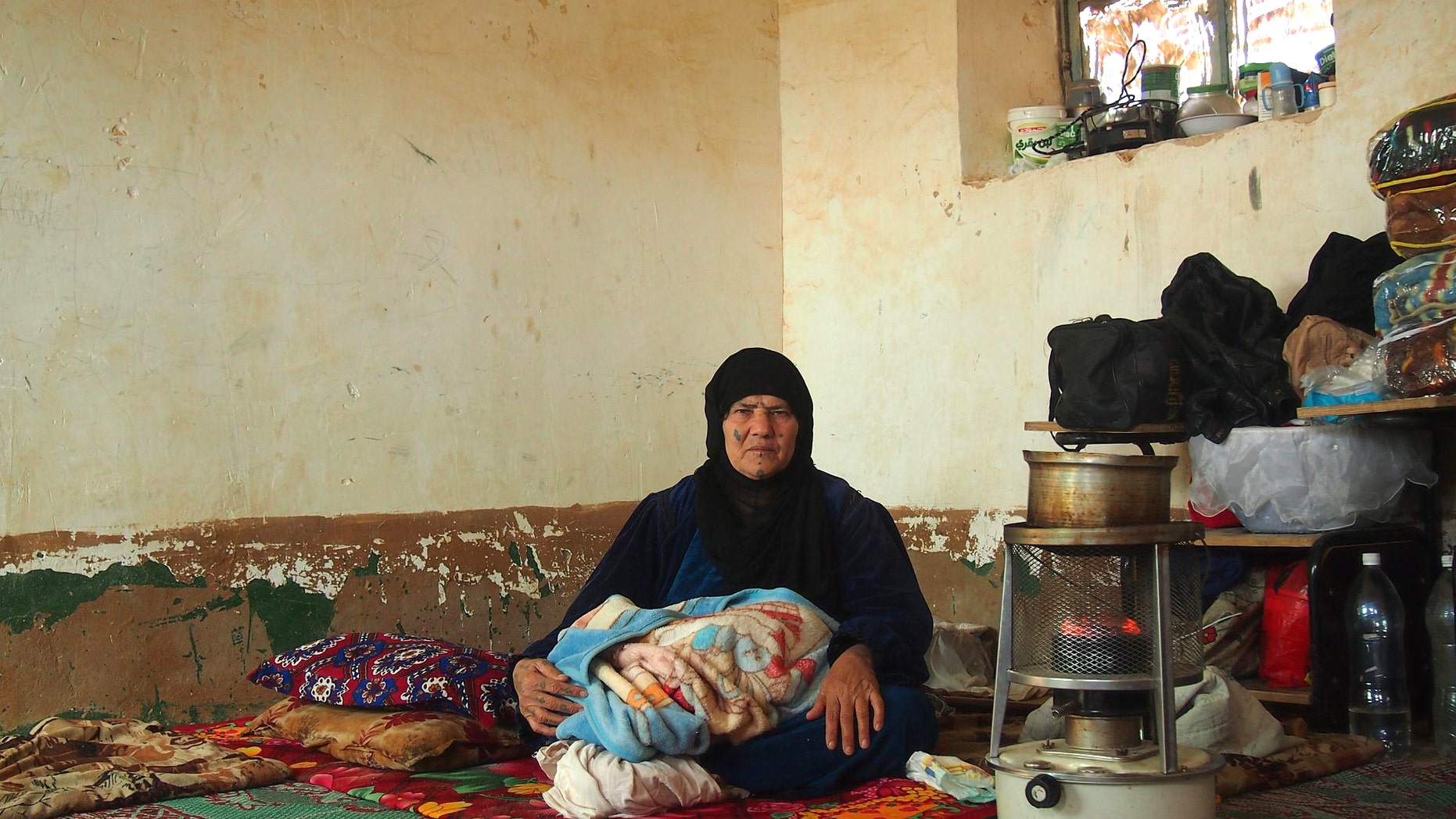 This image provided by the International Committee of the Red Cross (ICRC) on Wednesday, Jan. 15, 2014 shows an Iraqi mother fleeing the violence in Fallujah sits with her belongings in a provisional accommodation adapted from a classroom in Al-Rahhaliyah, south of Ramadi, Iraq. International aid agencies warned Wednesday, Jan. 15, 2014 that the continuing violence in Iraq’s western province of Anbar would bring more hardships to the locals and displaced people, as the country’s premier declared that the weeks-long standoff between security forces and the militants could take long time.(AP Photo/Majda Flihi, ICRC)