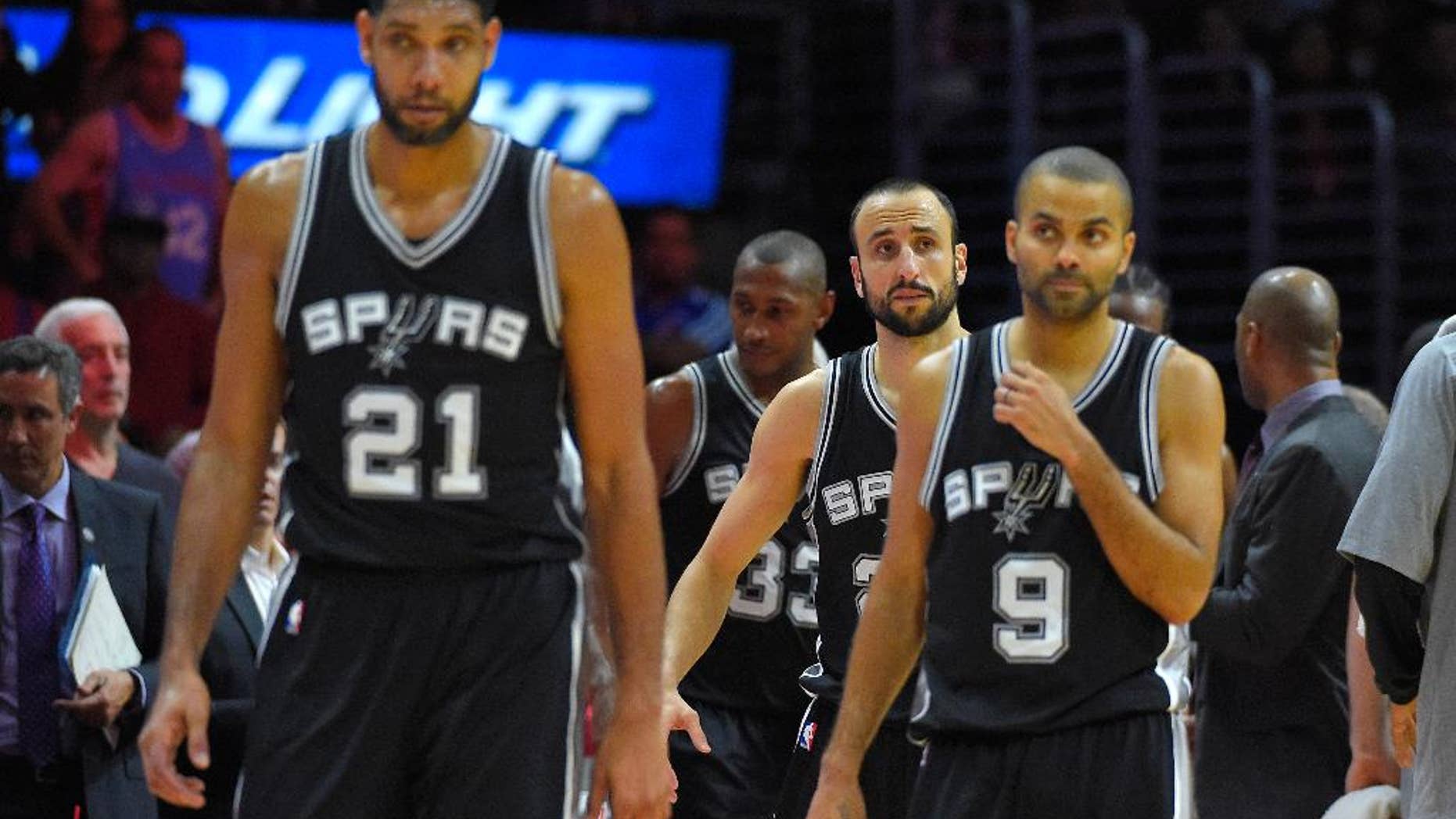 San Antonio Spurs forward Tim Duncan, left, guard Manu Ginobili, center, of Argentina, and guard Tony Parker, of France, look on during the second half of an NBA basketball game against the Los Angeles Clippers, Monday, Nov. 10, 2014, in Los Angeles. The Spurs won 89-85. (AP Photo/Mark J. Terrill)
