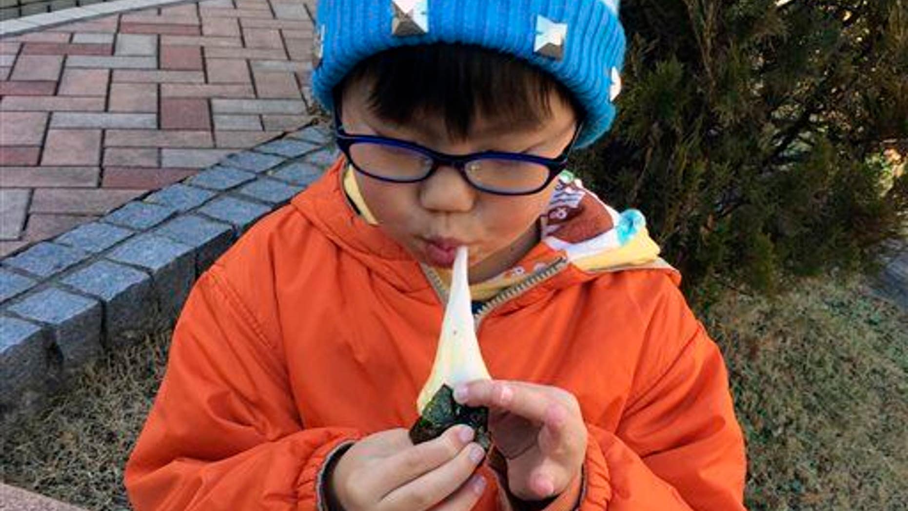 In this Dec. 13, 2014, photo, a boy eats a freshly pounded rice cake, or "mochi," wrapped in a sheet of seasoned laver, or "nori."