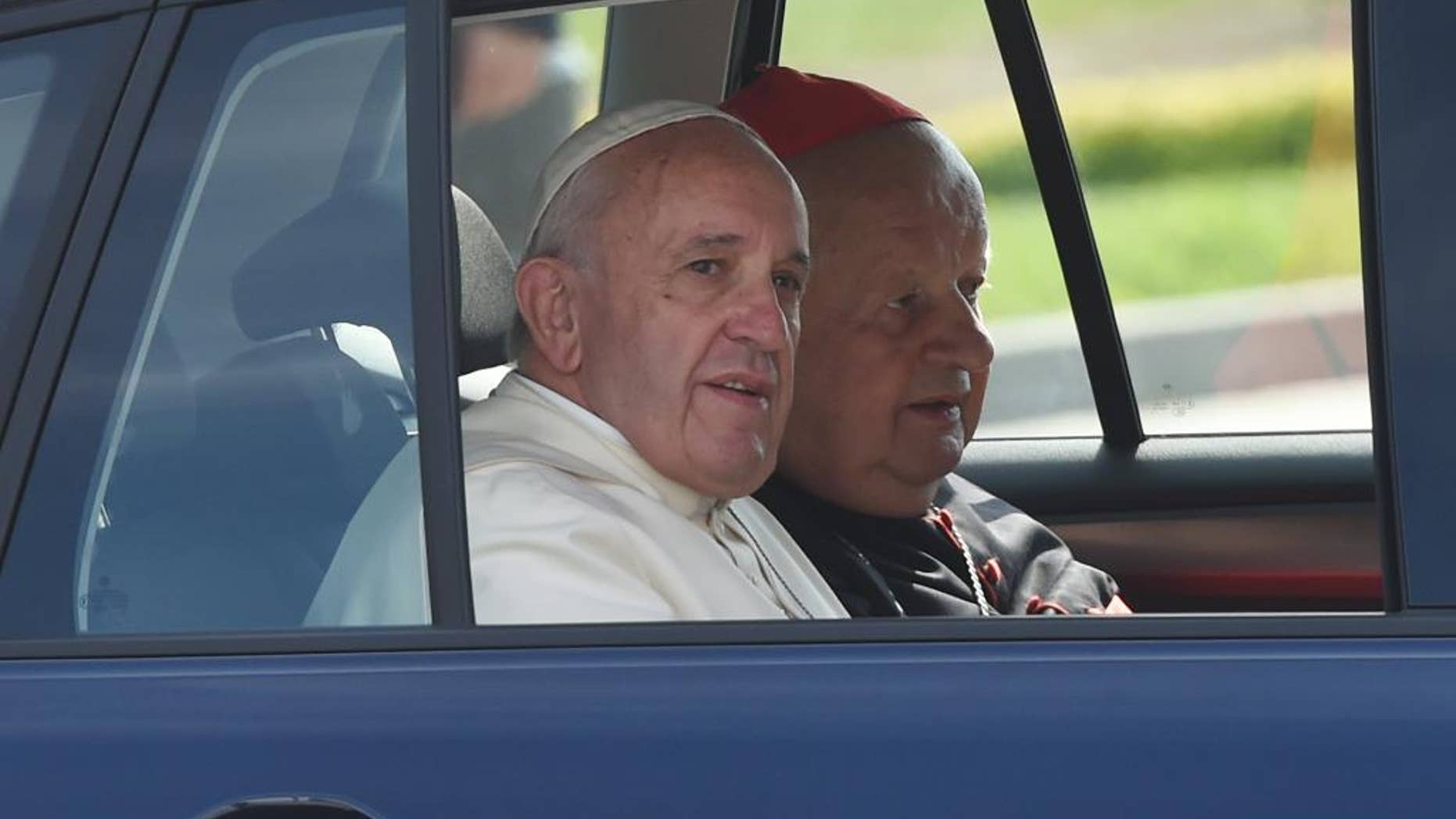 In this July 31, 2016 file photo pope Francis and Krakow cardinal Stanislaw Dziwisz, right, are arriving in a navy blue Volkswagen Golf car to celebrate a Holy Mass there. The car, along with two other similar VW Golf care that Francis was driven in in Poland has been put on auction by a Polish Catholic Church charity to raise funds for a mobile clinic for Syrian refugees in Lebanon and for a shelter for the disabled in Poland. (AP Photo/Alik Keplicz, file)