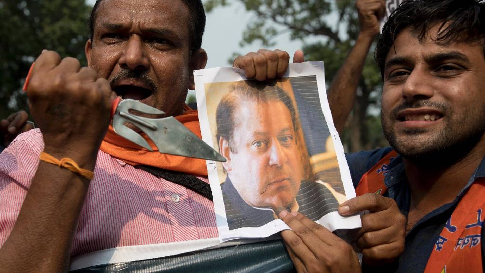 An activist of Hindu nationalist Shiv Sena party points a trident to a photograph of Pakistan Prime Minister Nawaz Sharif as they protest against Sunday's attack at an Indian army base in Kashmir, New Delhi, India, Monday, Sept. 19, 2016. India accuses Pakistan of training the militants in its territory, then helping them to infiltrate into the Indian side. Islamabad denies the charge, saying it only gives political and diplomatic support to the rebels. (AP Photo/Tsering Topgyal)