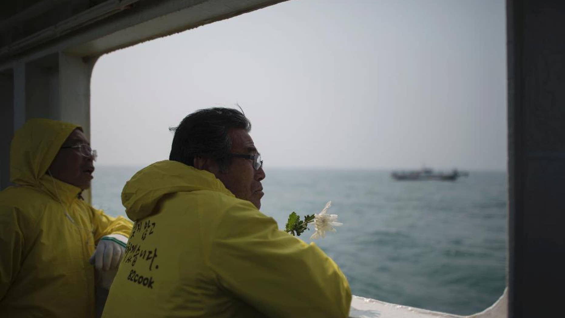 FILE - In this April 15, 2015, file photo, a relative of a victim of the ferry Sewol disaster watch the waters with flowers on the deck of a boat during a visit to the site of the sunken ferry, off the coast of South Korea's southern island of Jindo. It took divers in South Korea more than three agonizing days just to enter the ferry Sewol after it sank on April 16, 2014. (Ed Jones/Pool Photo via AP, File)
