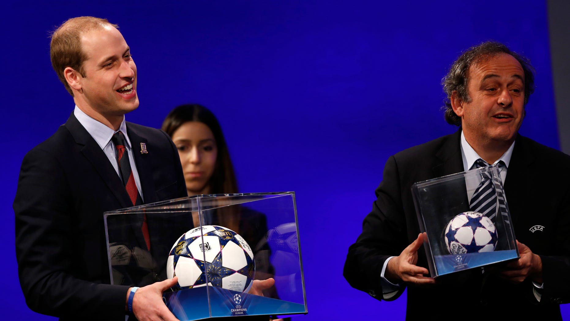 President of English Football Association Prince William, left, holding a football presented to him, reacts as UEFA President Michel Platini presents him with a mini soccer ball also after he addressed the delegates during the 37th Ordinary UEFA Congress in London, Friday, May 24, 2013. (AP Photo/Sang Tan)