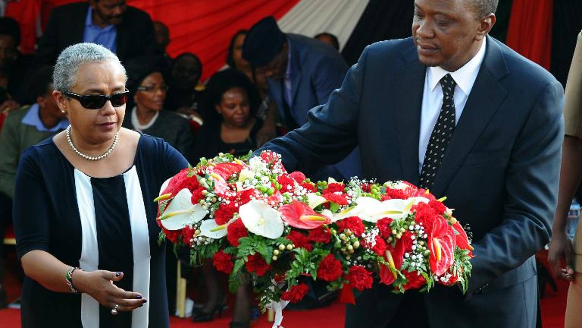 Kenyan President Uhuru Kenyatta and his wife Margaret lay a wreath of flowers during the funeral service of his nephew Mbugua Mwangi and his fiancee Rosemary Wahito in Nairobi on September 27, 2013