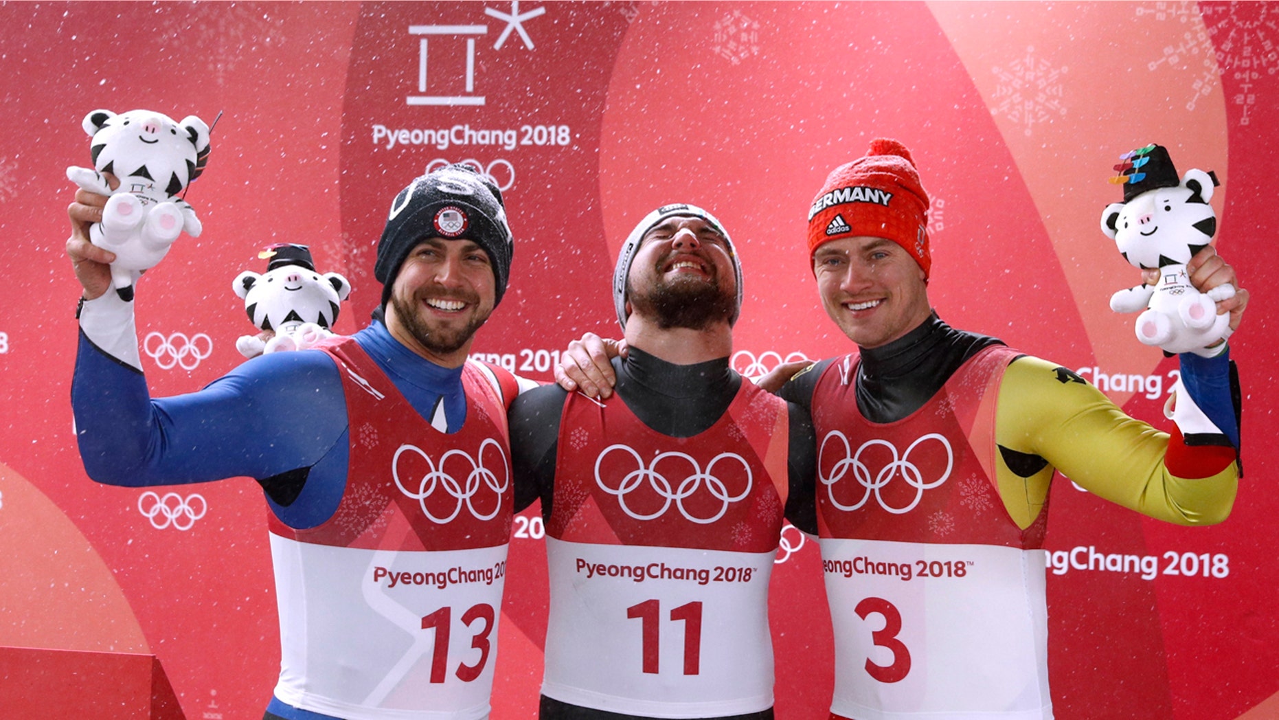 David Gleirscher of Austria, center, celebrates his men's singles luge win with 2nd-place Chris Mazdzer of the U.S. and 3rd-place Johannes Ludwig of Germany.