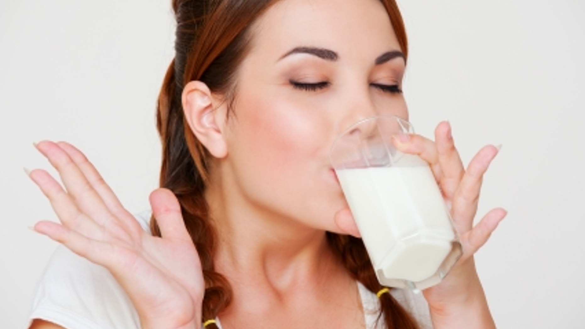 happy young woman drinking milk over grey background