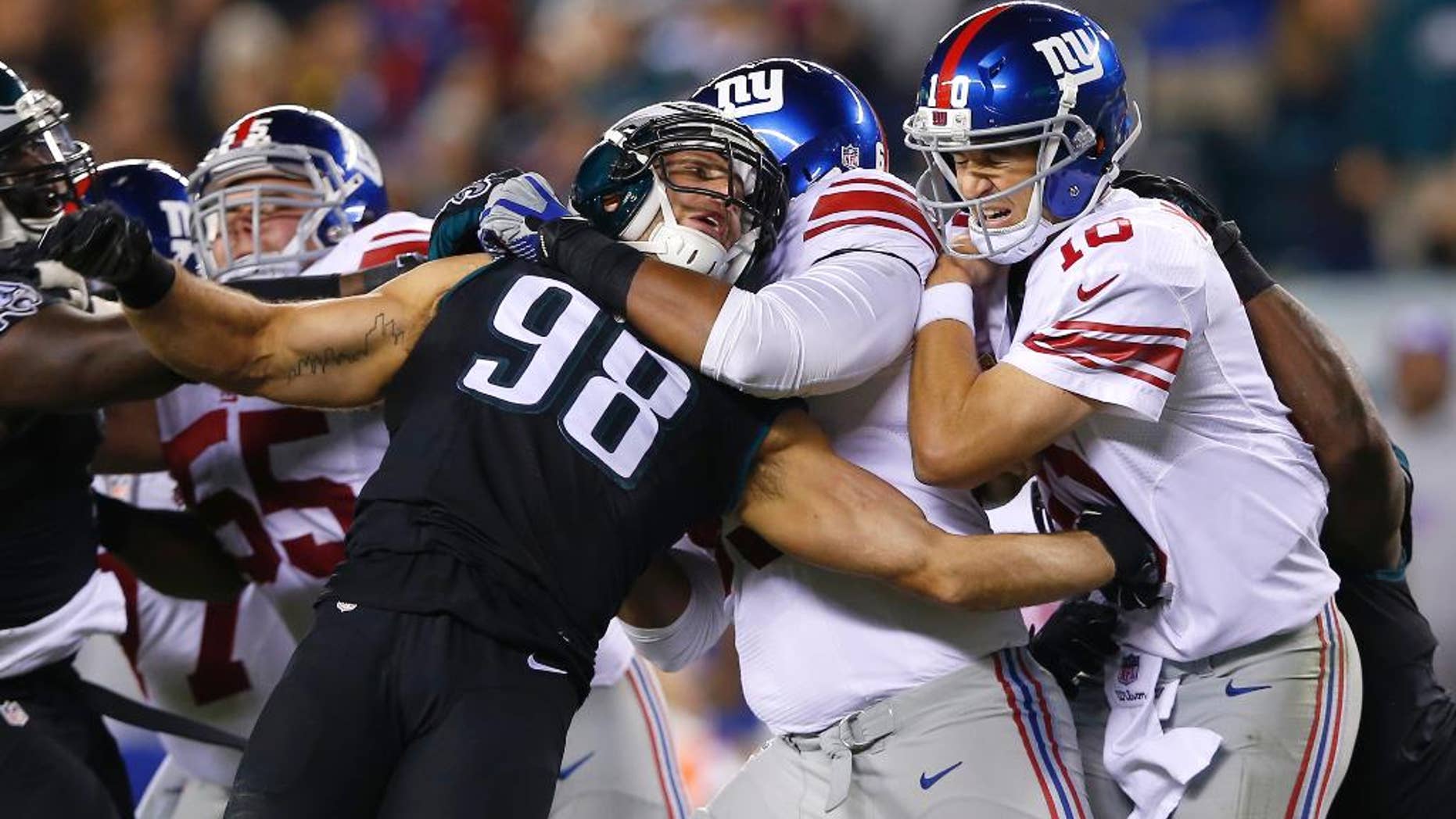 Philadelphia Eagles outside linebacker Connor Barwin (98) is held by New York Giants tackle Will Beatty, center left, as quarterback Eli Manning, center right, is hit by Eagles' Trent Cole, right, after throwing an incomplete pass during the second half of an NFL football game, Sunday, Oct. 12, 2014, in Philadelphia. (AP Photo/Michael Perez)