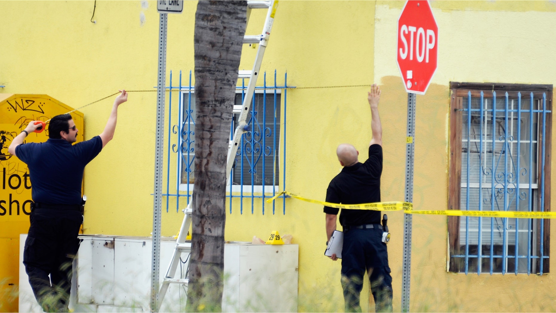 LOS ANGELES, CA - JUNE 25: Los Angeles Police Department investigators process the shooting scene across from the police station during a massive manhunt for a suspect who attempted to kill two detectives as they were returning to their station on June 25, 2013 in Los Angeles, California. The shooting happened in the early morning hours as the two detectives were ambushed and slightly injured outside the Los Angeles Police Department's Wilshire Station, prompting the closure of a 25-square-block area in the Mid-City section of Los Angeles. (Photo by Kevork Djansezian/Getty Images)