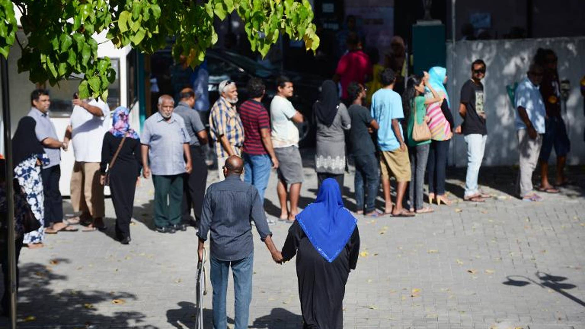 Two Maldivians walk towards the exit of a local polling station after having cast their vote in Male on September 7, 2013