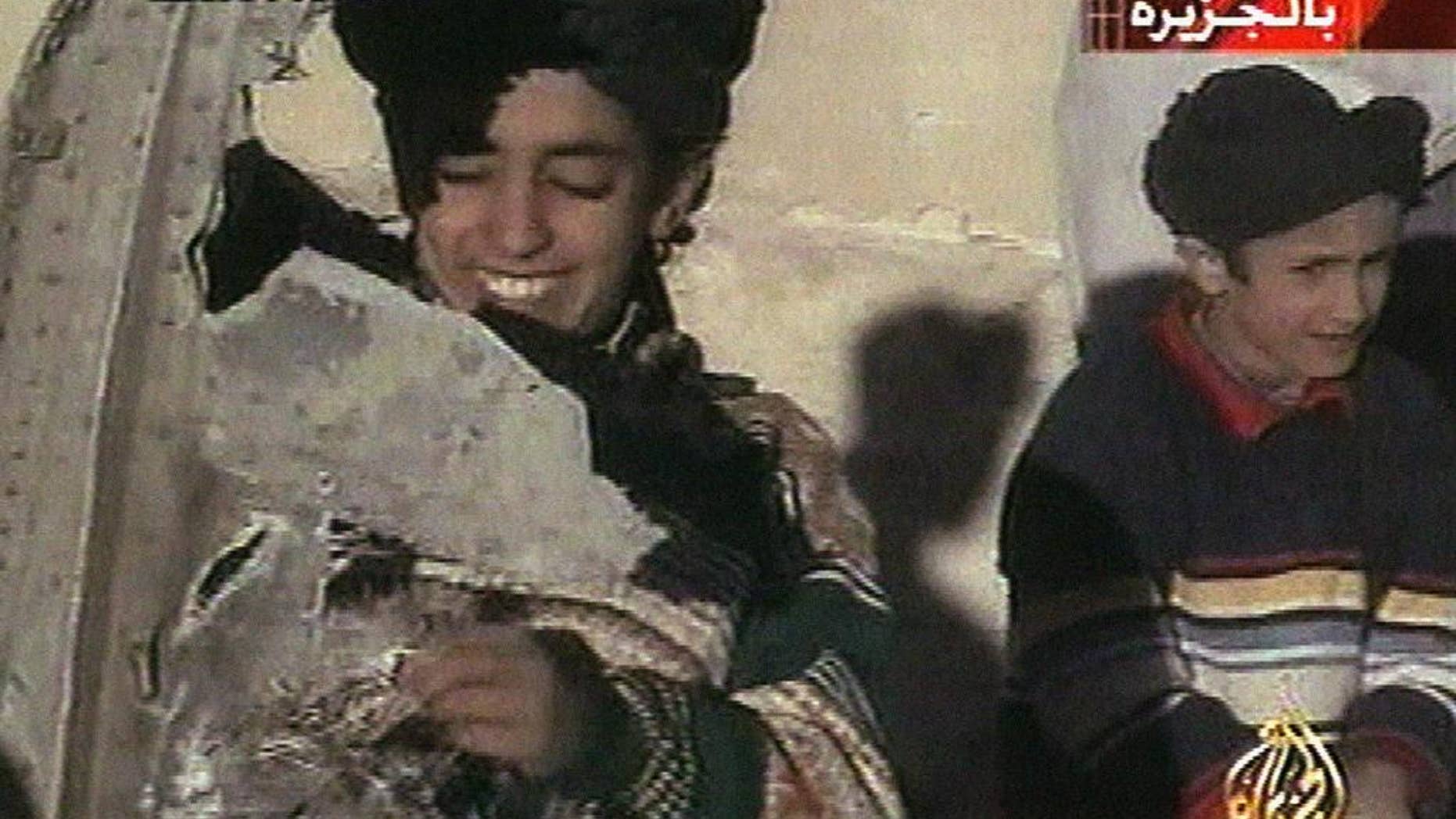 In this image made from video broadcast by the Qatari-based satellite television station Al-Jazeera Wednesday, Nov. 7, 2001, a young boy, left, identified as Hamza bin Laden holds what the Taliban says is a piece of U.S. helicopter wreckage in Ghazni, Afghanistan on Monday, Nov. 5, 2001. The Obama administration has announced terrorism-related sanctions against a son of Sept. 11 mastermind Osama bin Laden. The State Department says Hamza bin Laden has been “determined to have committed, or pose a serious risk of committing, acts of terrorism that threaten the security of U.S. nationals or the national security.” (AP Photo/Al-Jazeera via APTN) ** TV OUT **