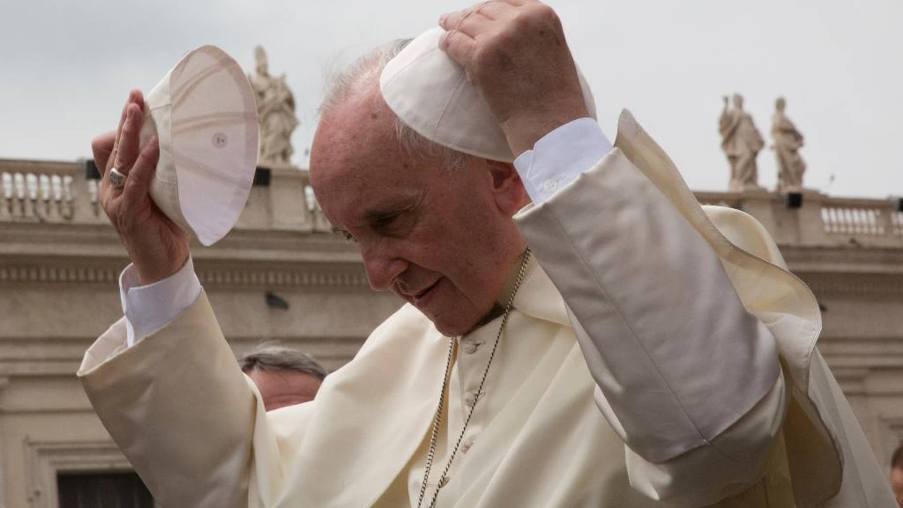 Pope Francis puts on a skull cap given by a worshipper as he leaves after his weekly general audience in St. Peter's Square at the Vatican, Wednesday, May 11, 2016. (AP Photo/Alessandra Tarantino)