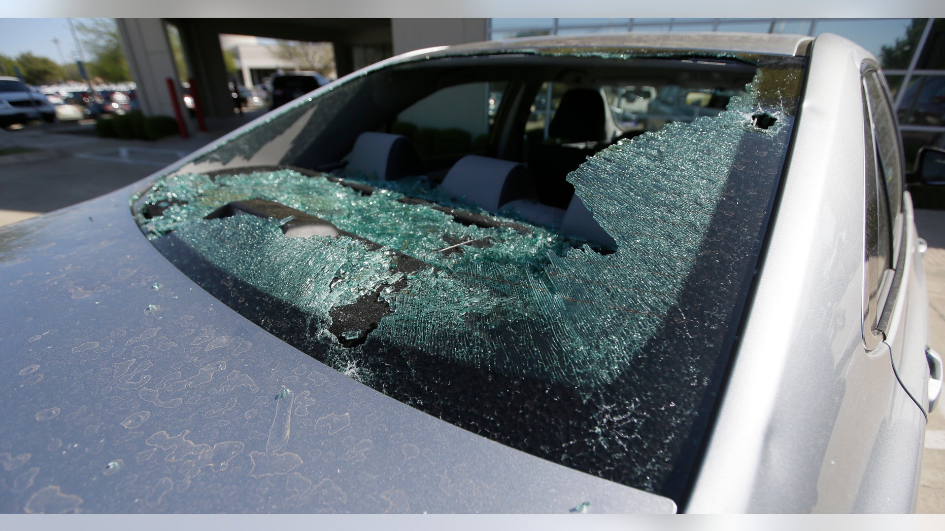 A car damaged by a hail storm sits in a parking lot in Plano, Texas.