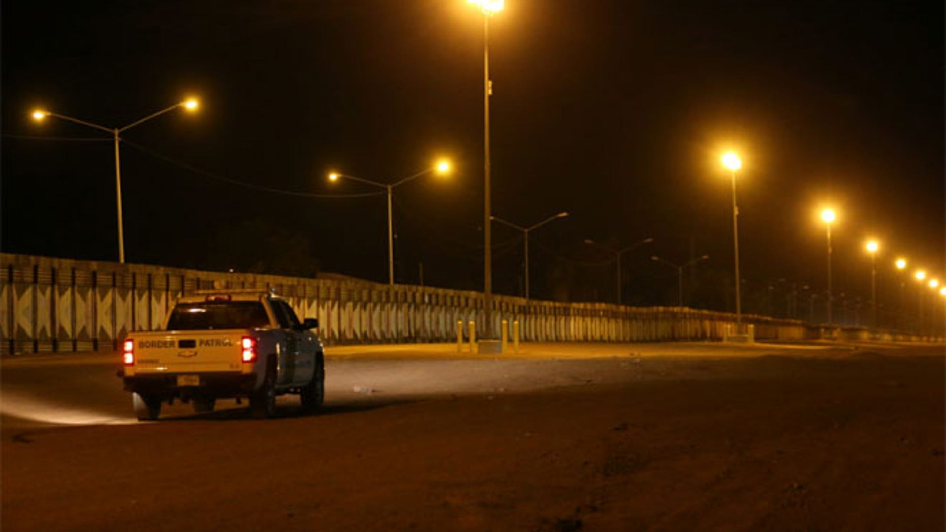 U.S. border patrol agents patrol at night along the border wall next to Mexico in Calexico, California