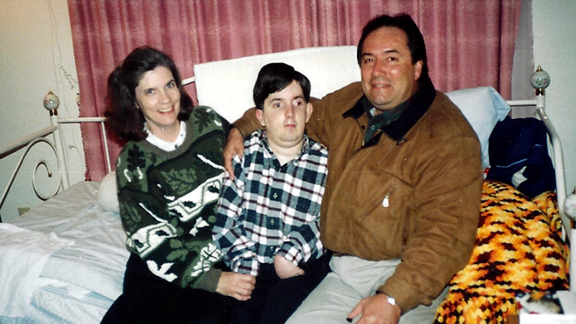 This undated handout photo provided by Paul Cortez shows 15-year-old Mikey Cortez, center, and his parents, Paul and Roonie Cortez. As his 7-year-old son Mikey lay in a hospital bed on life support, the victim of a drunk driver who had smashed into the car he was riding in, Paul Cortez took the boy's hand and made a solemn promise to God: If his son survived, no matter in what condition, he and his family would always be there for him. Although he would never emerge from the persistent vegetative state his father had found him in that night, Mikey's family was not only there for him but also gave him a full life. A life, as it turned out, not all that different from anybody else's, with cross-country family vacations and visits to Disneyland.(AP Photo/Courtesy Cortez Family)