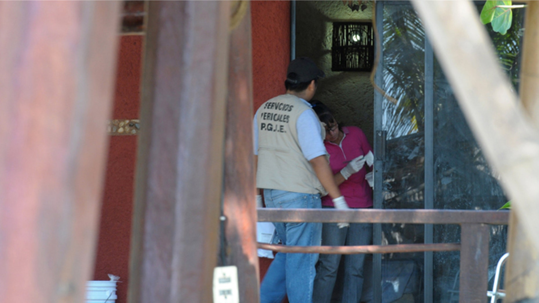 Police investigators work to obtain fingerprints on a door at the home where masked, armed men broke in, in Acapulco, Mexico, Tuesday Feb. 5, 2013. According to the mayor of Acapulco, five masked men burst into this house that Spanish tourists had rented on the outskirts of Acapulco, in a low-key area near the beach, and held a group of six Spanish men and one Mexican woman at gunpoint, while they raped the six Spanish women before dawn on Monday. (AP Photo/Bernandino Hernandez)