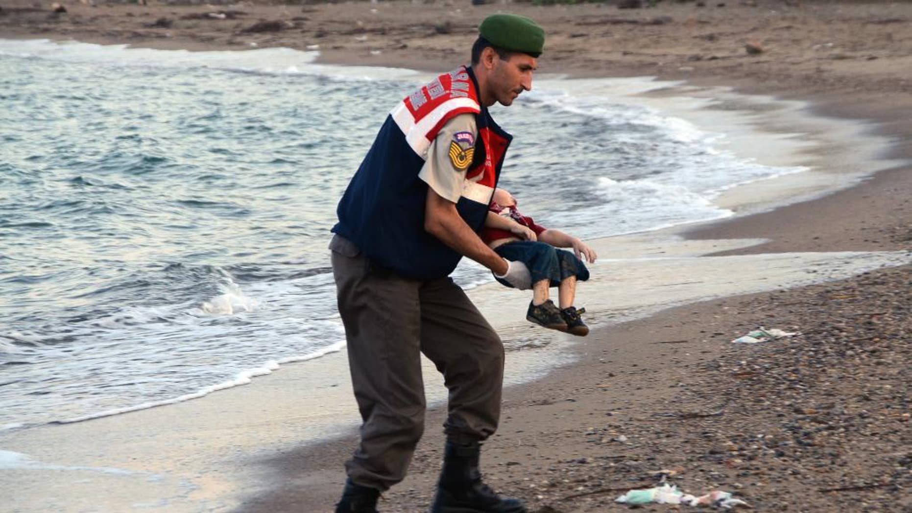 ADDS IDENTIFICATION OF CHILD A paramilitary police officer carries the lifeless body of Aylan Kurdi, 3, after a number of migrants died and a smaller number were reported missing after boats carrying them to the Greek island of Kos capsized, near the Turkish resort of Bodrum early Wednesday, Sept. 2, 2015. The family — Abdullah, his wife Rehan and their two boys, 3-year-old Aylan and 5-year-old Galip — embarked on the perilous boat journey only after their bid to move to Canada was rejected. The tides also washed up the bodies of Rehan and Galip on Turkey's Bodrum peninsula Wednesday, Abdullah survived the tragedy. (AP Photo/DHA) TURKEY OUT