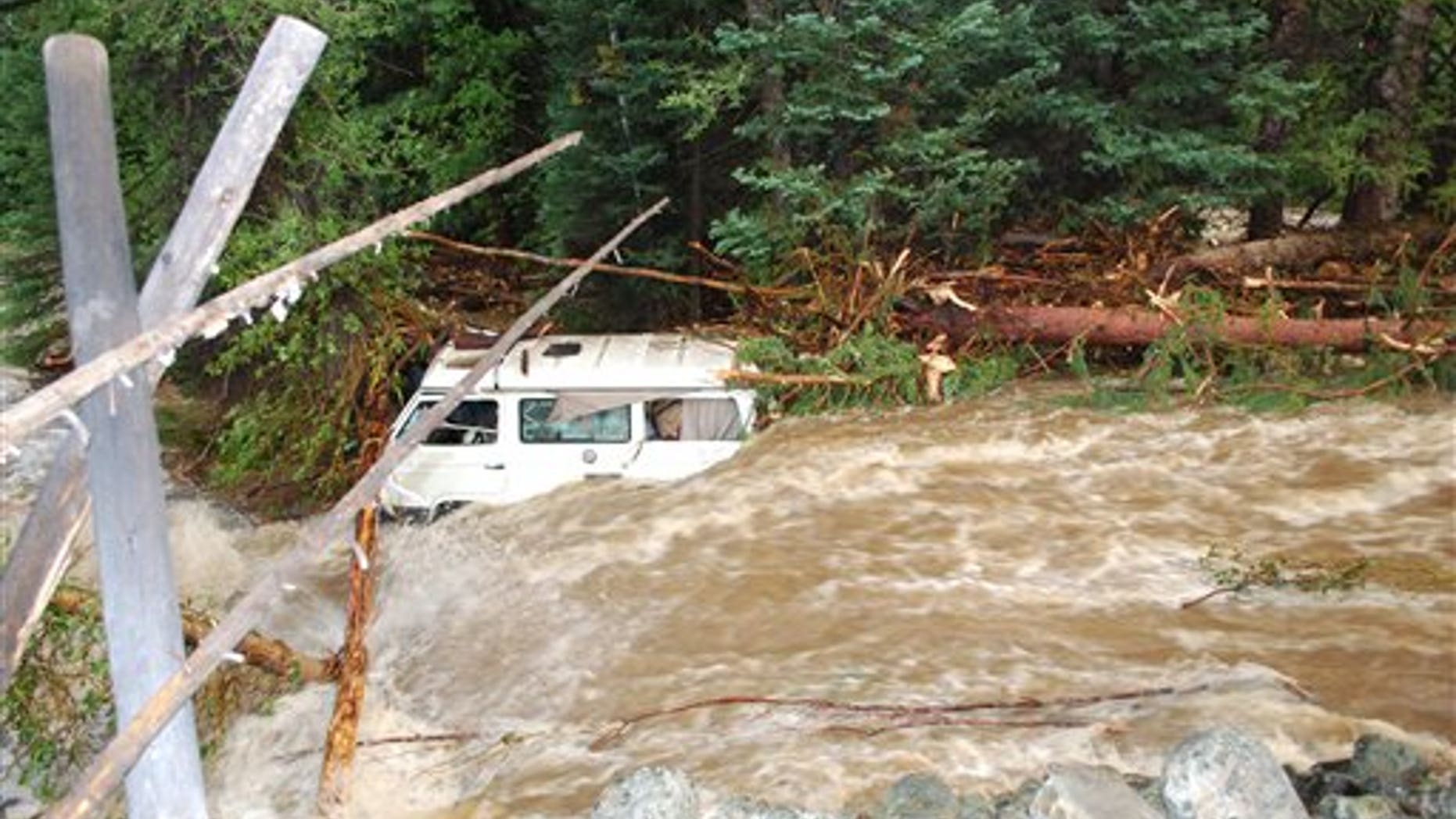 July 19: In this photo provided by Wyoming Highway Patrol, a van which was carrying four members of a family who died, is seen downstream from washed-out section of Wyoming Highway 130 in the Medicine Bow Mountains in southern Wyoming. They were fleeing torrential rains at a national forest campground.