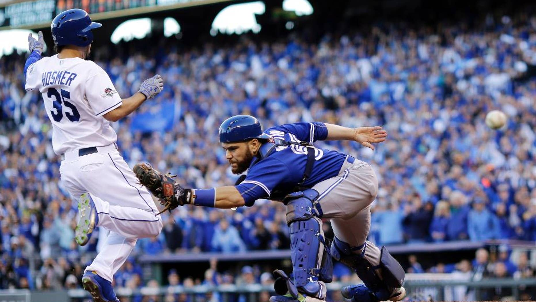 Toronto Blue Jays catcher Russell Martin misses the throw to home plate as Kansas City Royals' Eric Hosmer, right, comes in to score during the seventh inning in Game 2 of baseball's American League Championship Series, Saturday, Oct. 17, 2015, in Kansas City, Mo. (AP Photo/Matt Slocum)