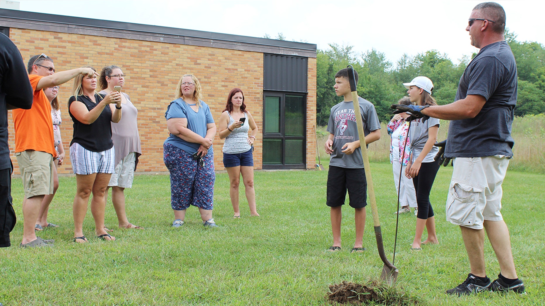 In this Sunday, Aug. 26, 2018, photo classmates that were in the AWARE classes at Coloma Junior High School in 1988 try to find a time capsule that they buried behind the school in Coloma, Mich., that year. The Herald-Palladium reports that the seven classmates and two teachers spent two hours on Sunday digging outside Coloma Junior High in southwestern Michigan.