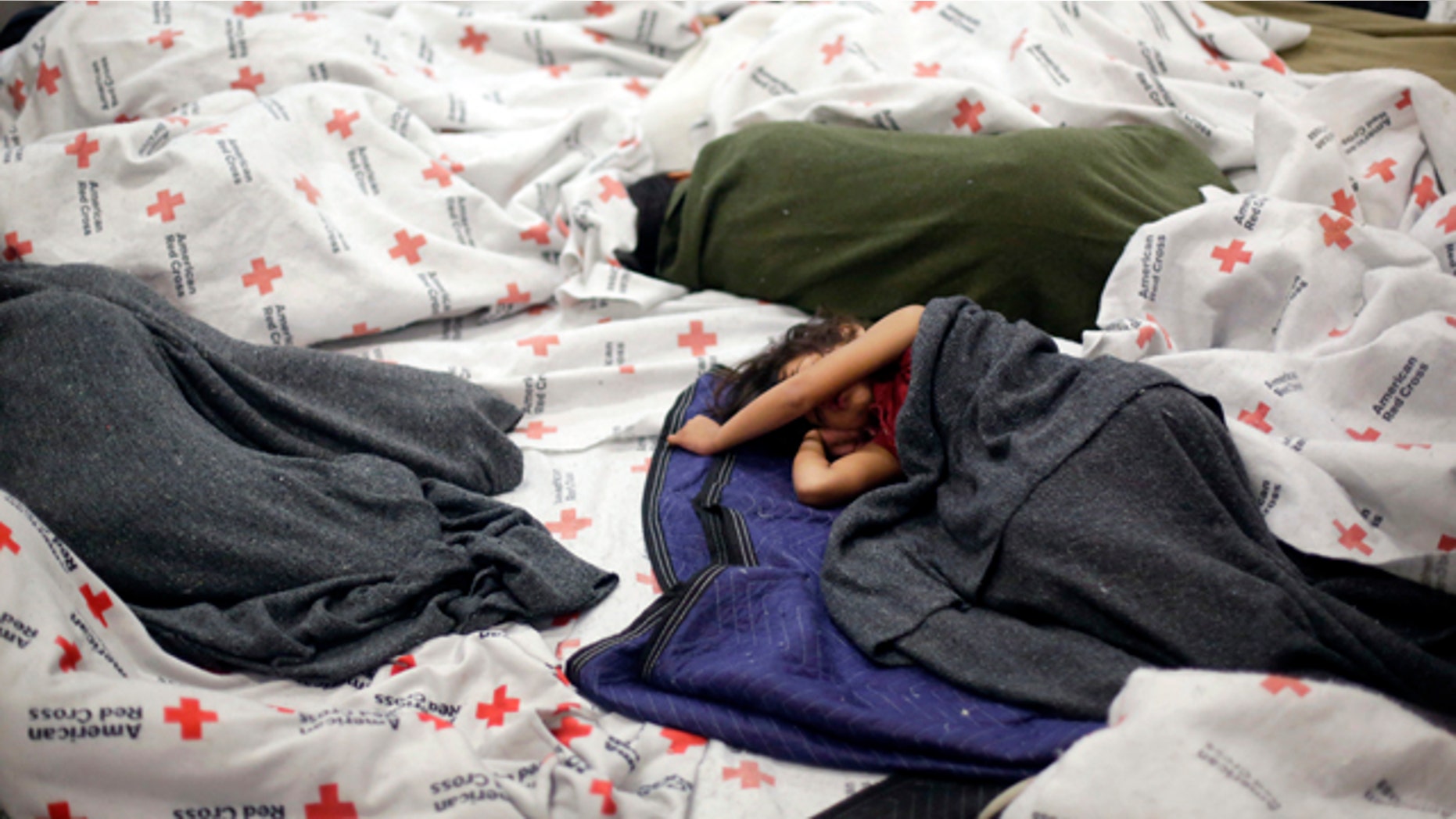 June 18, 2014: Detainees sleep in a holding cell at a U.S. Customs and Border Protection processing facility in Brownsville,Texas. (AP Photo/Eric Gay, Pool)