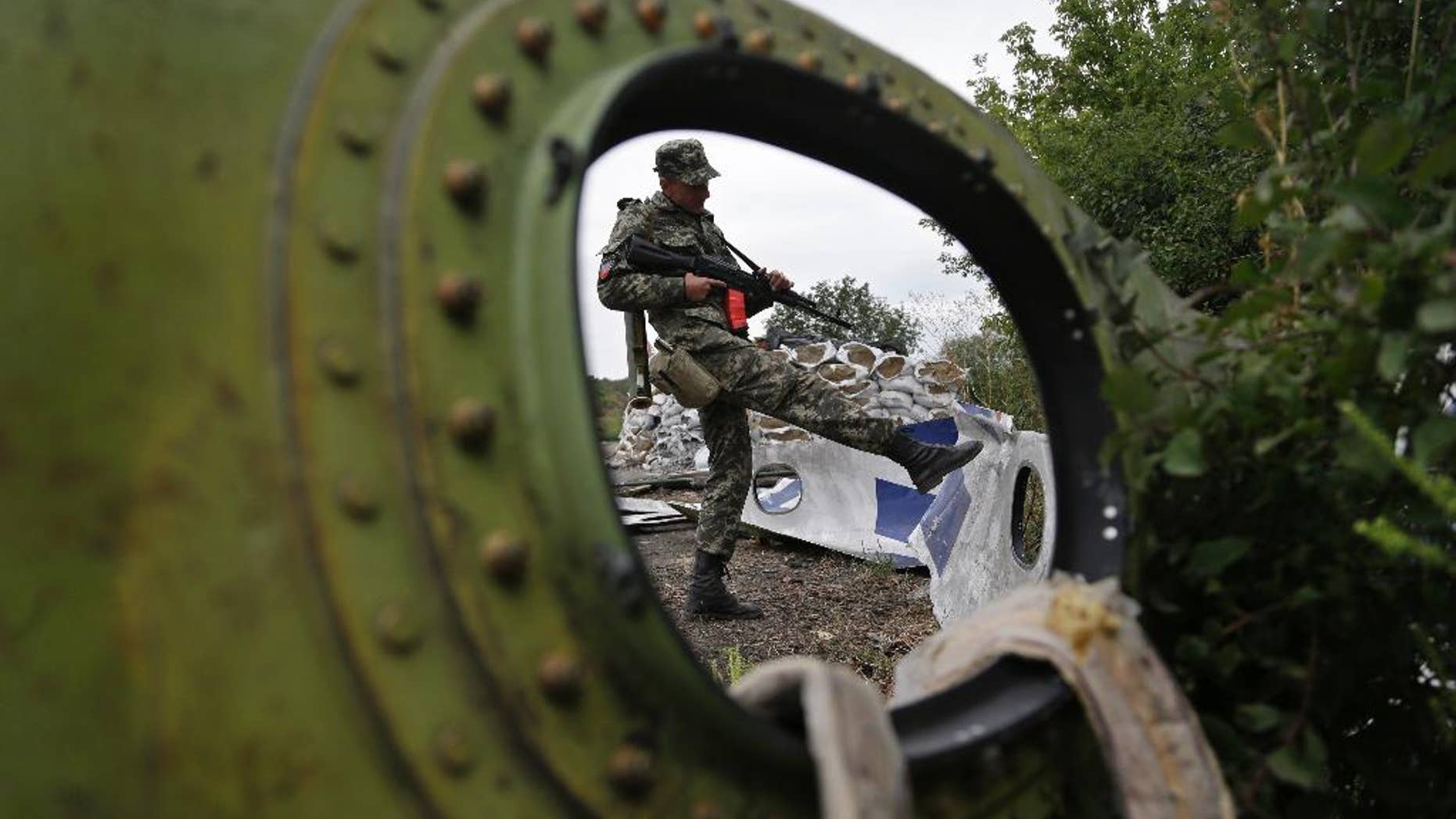 AP10ThingsToSee- A Pro-Russian rebel looks at pieces of the Malaysia Airlines Flight 17 plane near village of Rozsypne, eastern Ukraine, Tuesday, Sept. 9, 2014. The Dutch team investigating the downing of Malaysia Airlines Flight 17 over Eastern Ukraine says the crash was likely caused by the plane being hit by multiple "high-energy objects from outside the aircraft." (AP Photo/Sergei Grits)