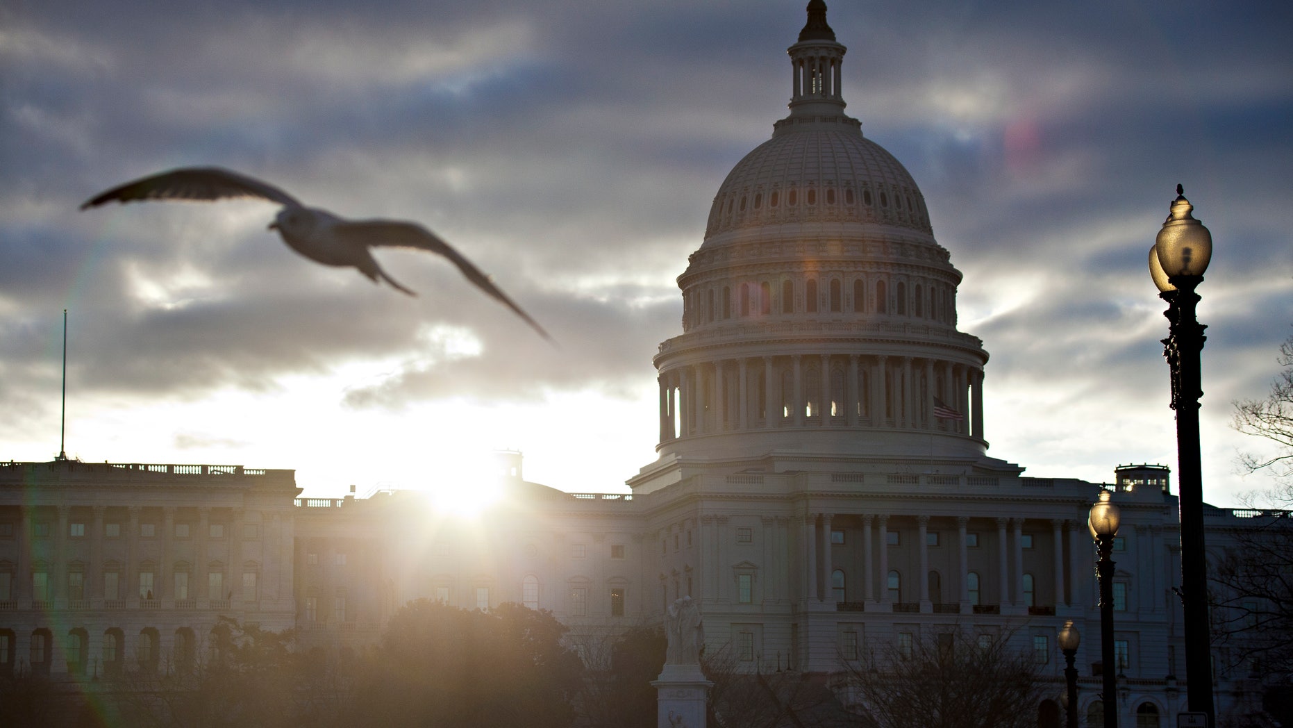 FILE -- At dawn, the sun breaks through dark clouds over Capitol Hill in Washington.