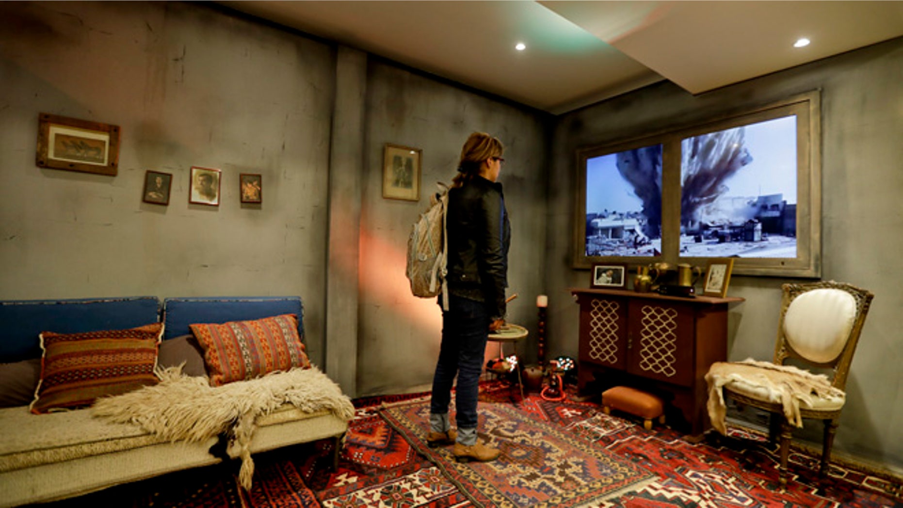 A woman watches a video of an explosion as she stands inside a mock-up Syrian home, set up by Amnesty International inside a subway station, in Buenos Aires, Argentina, Monday, Sept. 19, 2016.