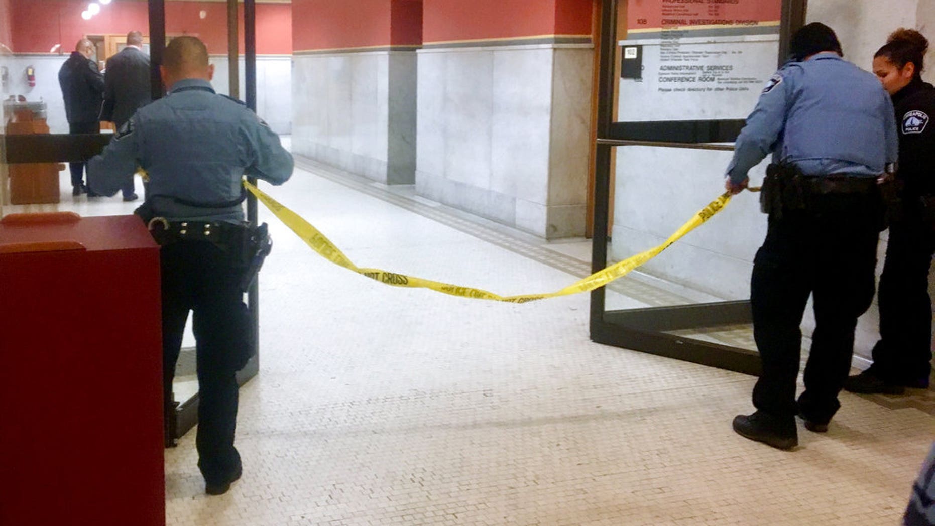 Police set up crime scene tape outside a Minneapolis police room at Minneapolis City Hall on Monday, Dec. 18, 2017. Minneapolis police say their officers have been involved in a shooting inside the department's investigative unit at City Hall. (AP Photo/Jeff Baenen)