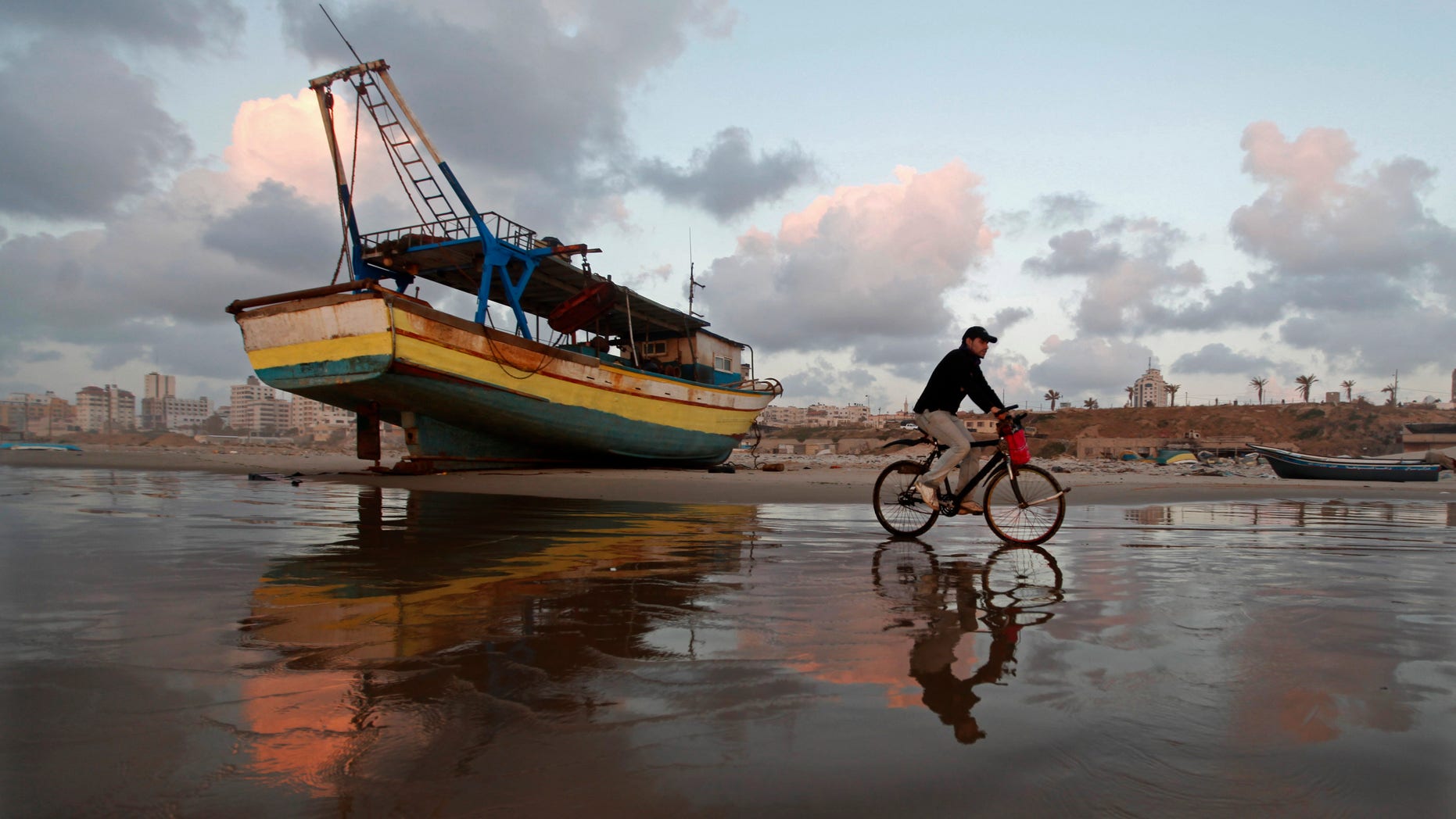 A Palestinian man rides a bicycle on the beach of Gaza City during sunset on Tuesday. April 9, 2013. (AP Photo/Hatem Moussa)