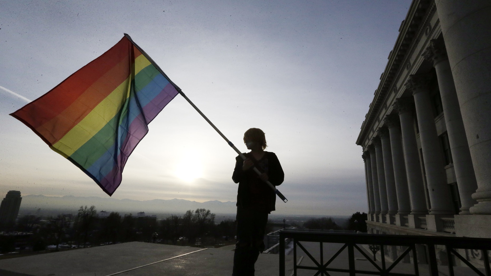 Corbin Aoyagi, a supporters of gay marriage, waves his flag during a rally at the Utah State Capitol.