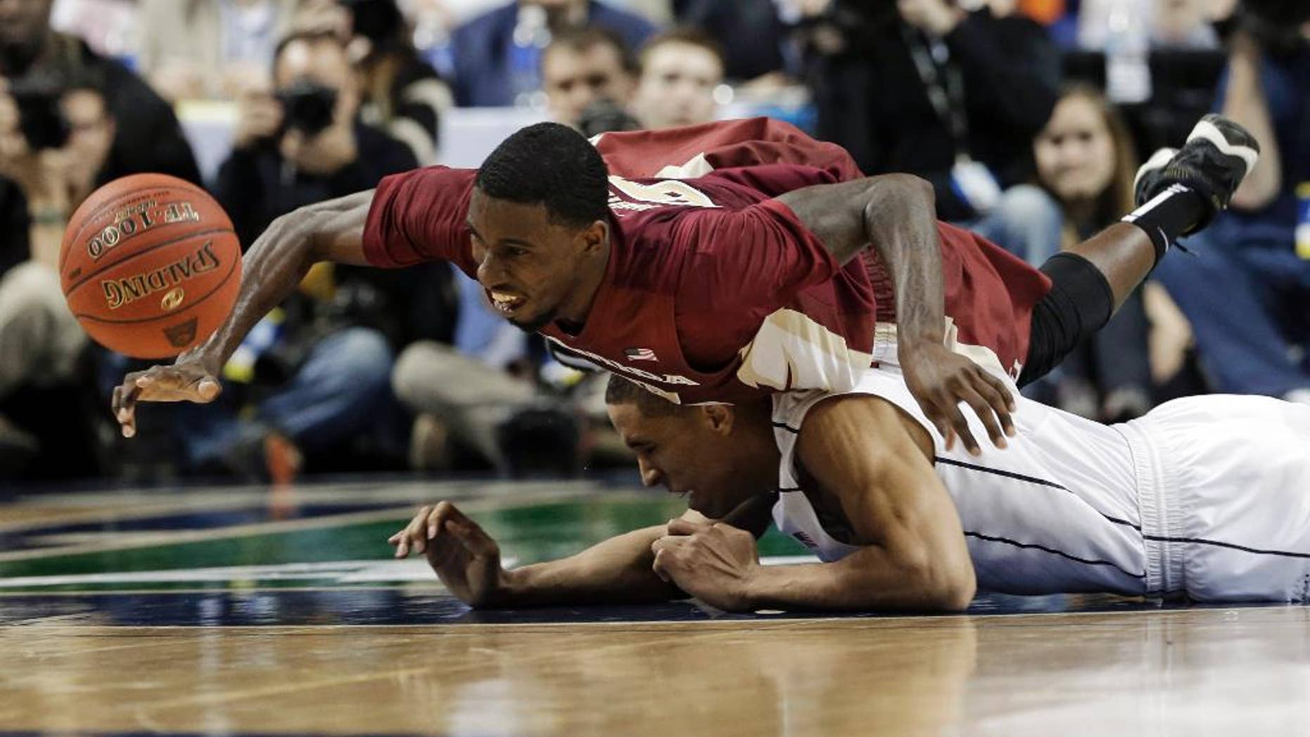 Florida State's Okaro White, top, falls over Virginia's Malcolm Brogdon, bottom, as they chase a loose ball during the second half of an NCAA college basketball game in the quarterfinal round of the Atlantic Coast Conference tournament in Greensboro, N.C., Friday, March 14, 2014. (AP Photo/Gerry Broome)