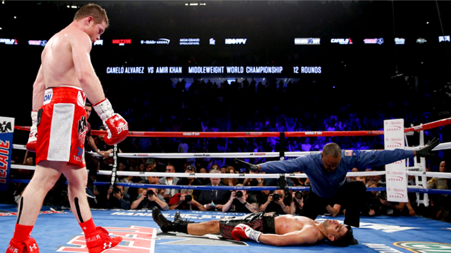 Canelo Alvarez, left, watches after knocking down Amir Khan during their WBC middleweight title fight Saturday, May 7, 2016, in Las Vegas. (AP Photo/John Locher)