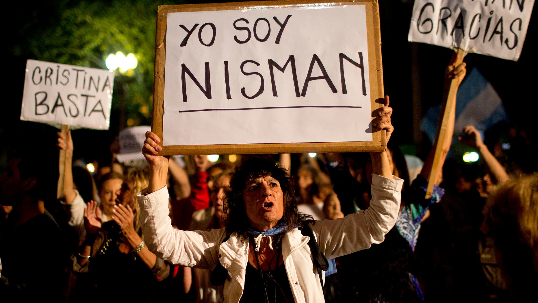 A demonstrator holds a sign that reads in Spanish "I am Nisman" during a protest sparked by the death of special prosecutor Alberto Nisman, outside the government house in Plaza de Mayo in Buenos Aires, Argentina, Monday, Jan. 19, 2015. The other signs read "Enough Cristina," left, and "Thank you Nisman." Nisman, who had been investigating the 1994 bombing of the AMIA Jewish community center in Buenos Aires that killed 85 people and who accused President Cristina Fernandez of shielding Iranian suspects, was found dead with a gunshot to his head in the bathroom of his apartment late Sunday, hours before he was to testify in a Congressional hearing about the case. (AP Photo/Rodrigo Abd)
