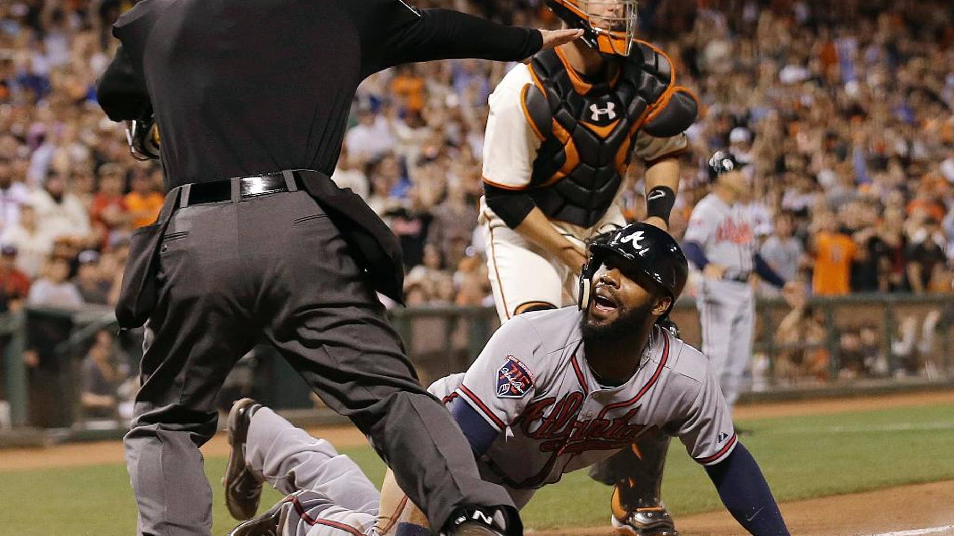 Atlanta Braves' Jason Heyward, bottom, is called safe at home by umpire Ed Hickox, left, in front of San Francisco Giants catcher Buster Posey during the sixth inning of a baseball game in San Francisco, Tuesday, May 13, 2014. Giants manager Bruce Bochy challenged the ruling but the play stood. The Braves won 5-0. (AP Photo)