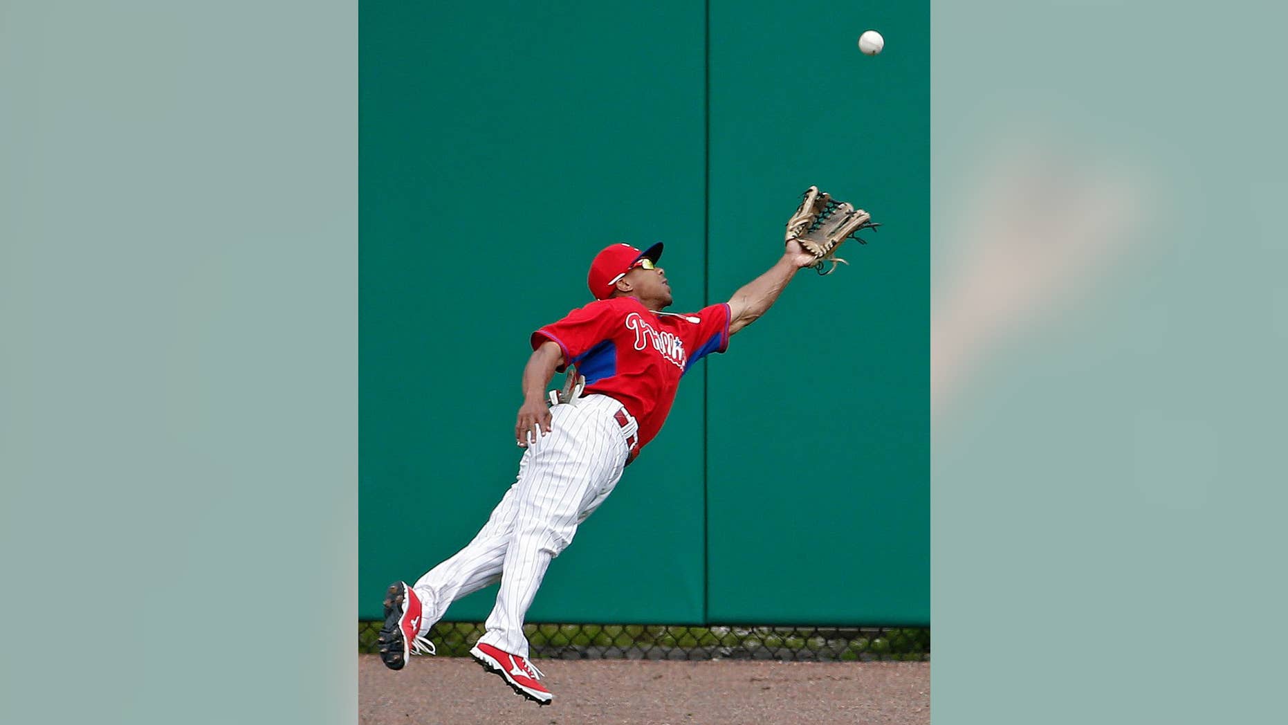Philadelphia Phillies center fielder Ben Revere (2) dives for Atlanta Braves Gerald Laird's fourth-inning double in a spring exhibition baseball game in Clearwater, Fla., Monday, March 10, 2014. (AP Photo/Kathy Willens)