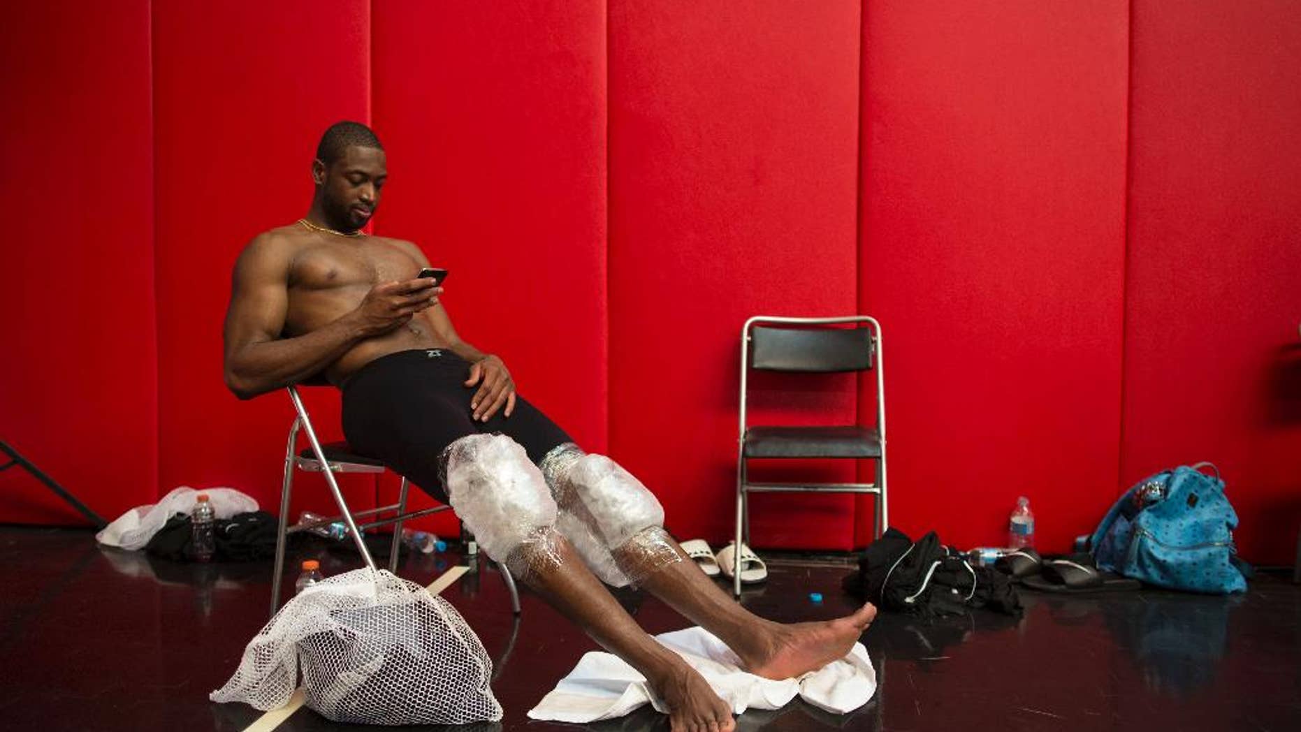 Miami Heat's Dwyane Wade rests with his knees wrapped in ice packs after practice in Rio de Janeiro, Brazil, Friday, Oct. 10, 2014. Miami Heat will play Cleveland Cavaliers in a pre-season game on Saturday as part of the NBA Global Games. (AP Photo/Felipe Dana)