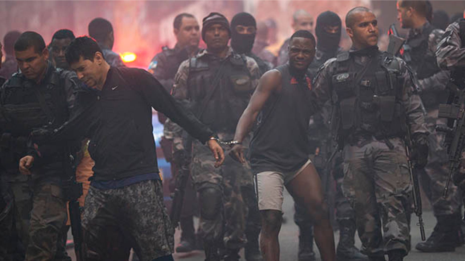 Police move a couple of handcuffed, recently detained men in Rio de Janeiro, Brazil, Monday, Oct. 10, 2016.