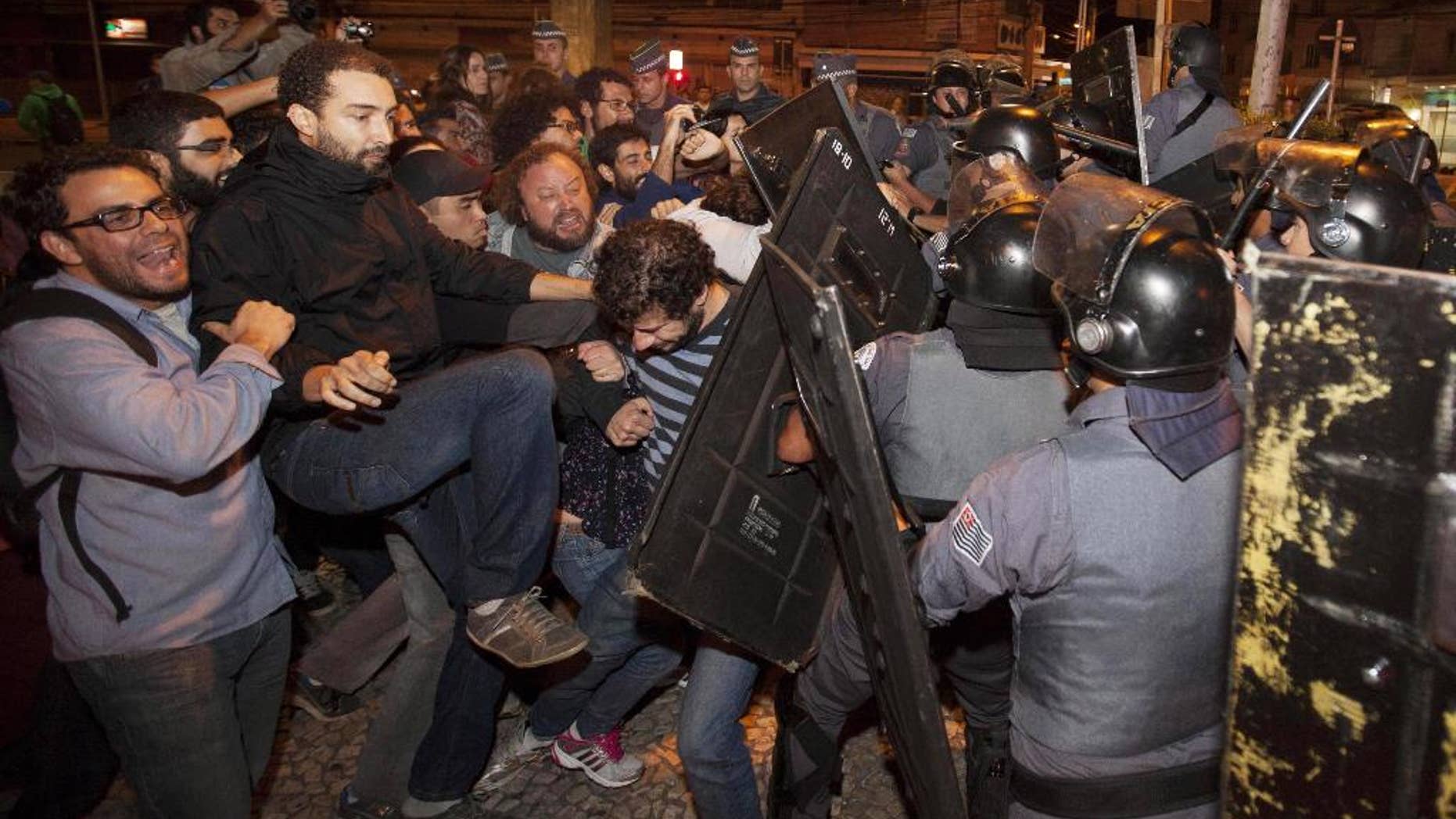 Subway train operators, along with activists from social movements, clash with riot police in front of the Ana Rosa metro station, in an ongoing subway strike, in Sao Paulo, Brazil, Monday, June 9, 2014. Authorities are deeply worried about the strike because the subway is the main means of transportation for World Cup fans scheduled to attend Thursday's opening match when Brazil takes on Croatia. The stadium is about 20 kilometers (12 miles) east of central Sao Paulo, where most tourists stay. (AP Photo/Mario Angelo)