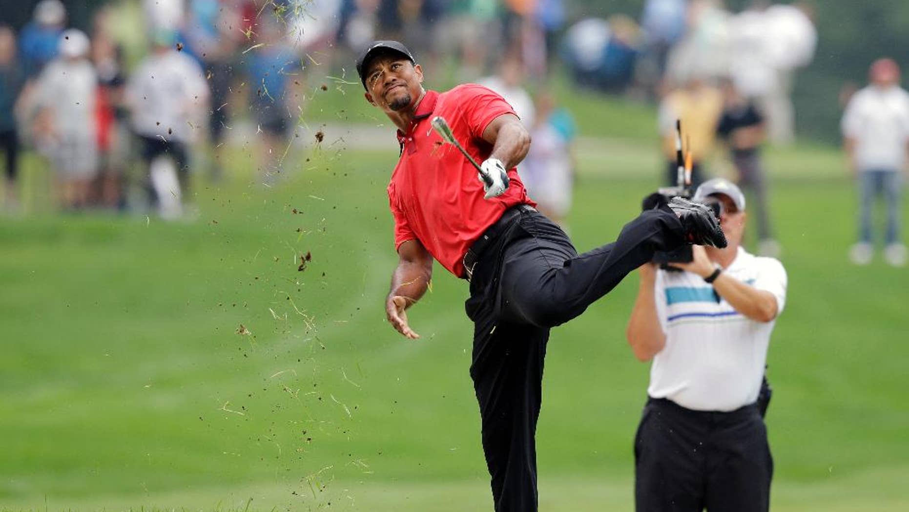 Tiger Woods makes an awkward follow through after hitting from the lip of a fairway bunker on the second hole during the final round of the Bridgestone Invitational golf tournament Sunday, Aug. 3, 2014, at Firestone Country Club in Akron, Ohio. (AP Photo/Mark Duncan)