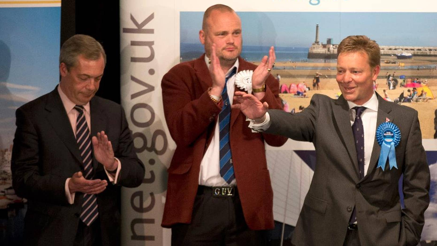 The Conservative Party's Craig Mackinlay, right, waves after winning the count for the South Thanet seat beside, from left, Nigel Farage the leader of the UK Independence Party (UKIP) and Al Murray a comedian who performs as "The Pub Landlord" at the Winter Gardens in Margate, south east England, Friday, May 8, 2015. British Prime Minister David Cameron appeared poised to remain in power Friday, with early British election results and exit polls indicating his Conservatives had won a resounding victory and will return to 10 Downing Street in a stronger position than before. (AP Photo/Matt Dunham)