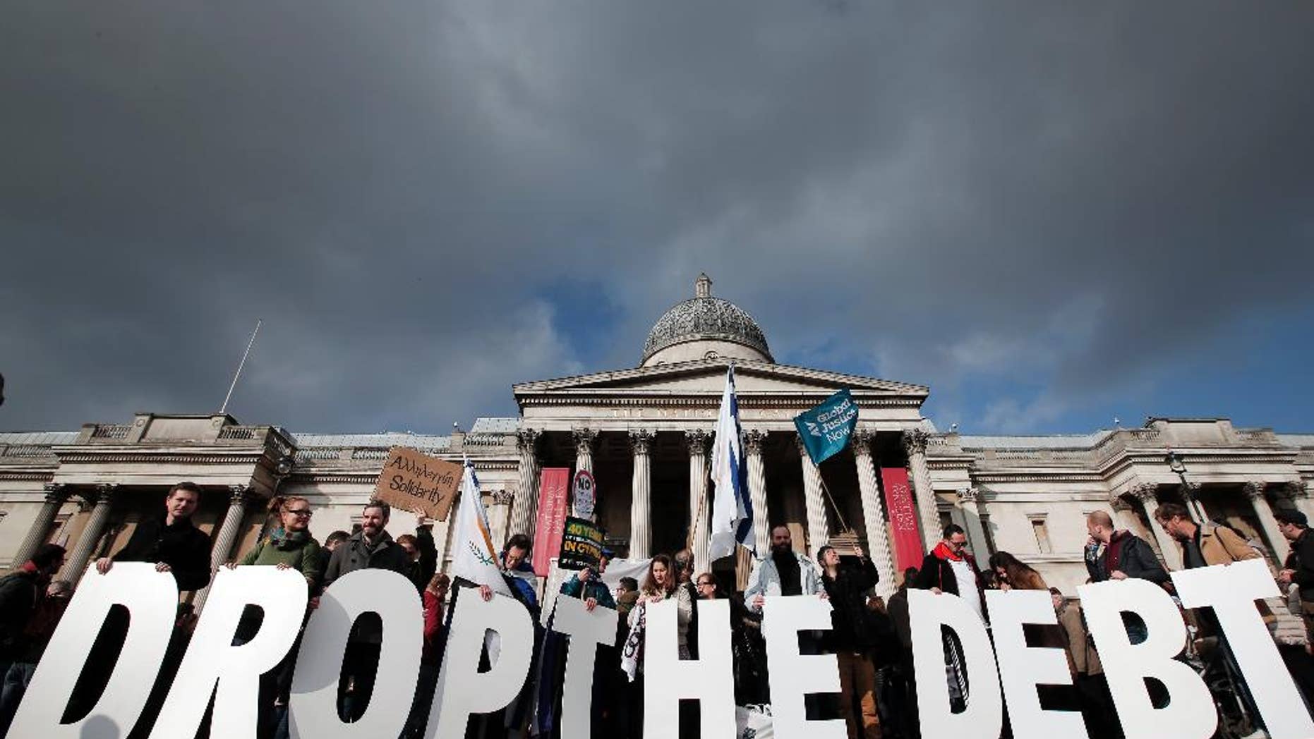Protesters hold placards during a rally to show solidarity with Greece in central London, Sunday, Feb. 15, 2015. Hundreds of protesters gathered in support of the new government and the anti-austerity movement in Greece. Greece's new left-wing government is pressing for a short-term "bridge" agreement with eurozone lenders and a longer-term debt relief deal later this year. (AP Photo/Lefteris Pitarakis)