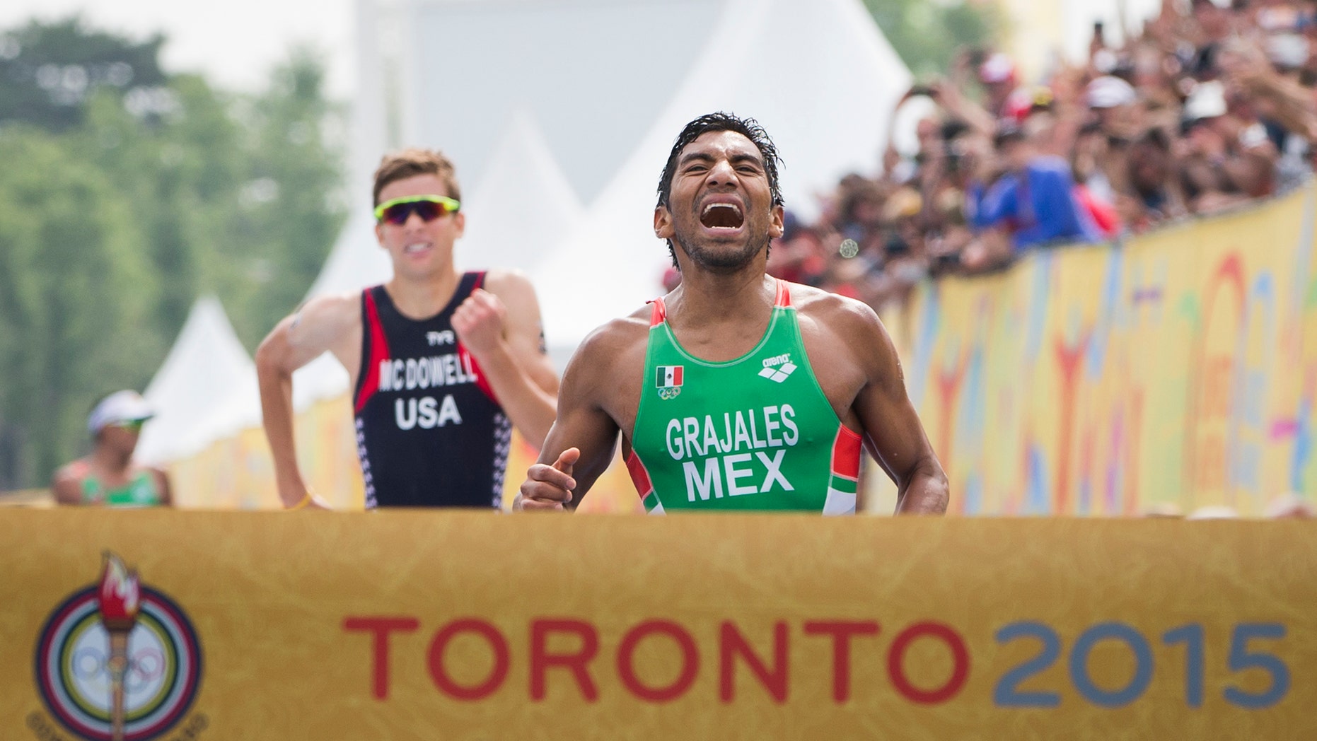 Mexico's Crisanto Grajales, right, reacts before crossing the finish line to win the gold medal ahead of United States' Kevin McDowell during the Men's Triathlon at the Pan Am Games in Toronto, Ontario, Sunday, July 12, 2015. (AP Photo/Felipe Dana)